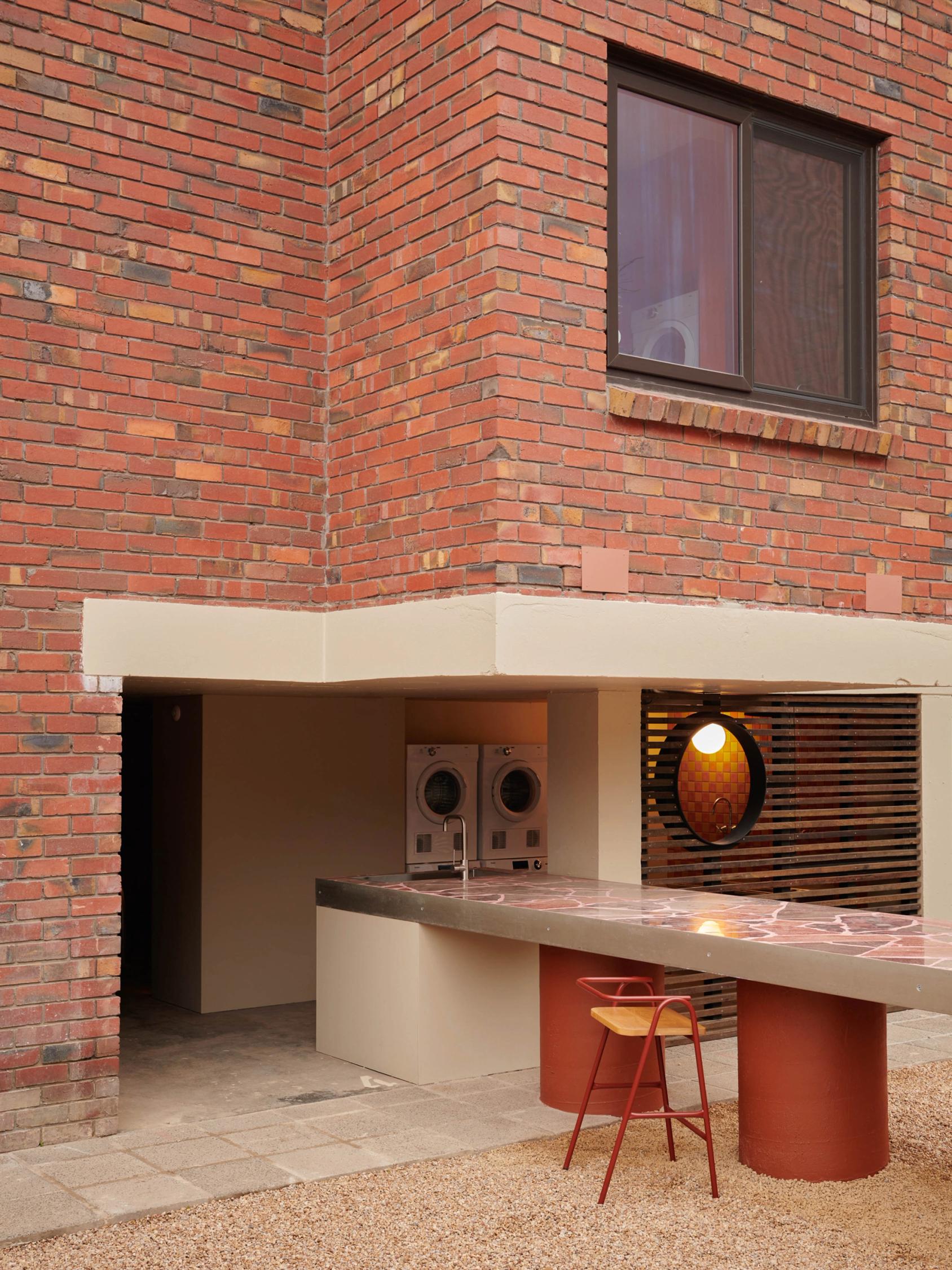 Partially outdoor laundry underneath apartment building, with dining space extending outside.