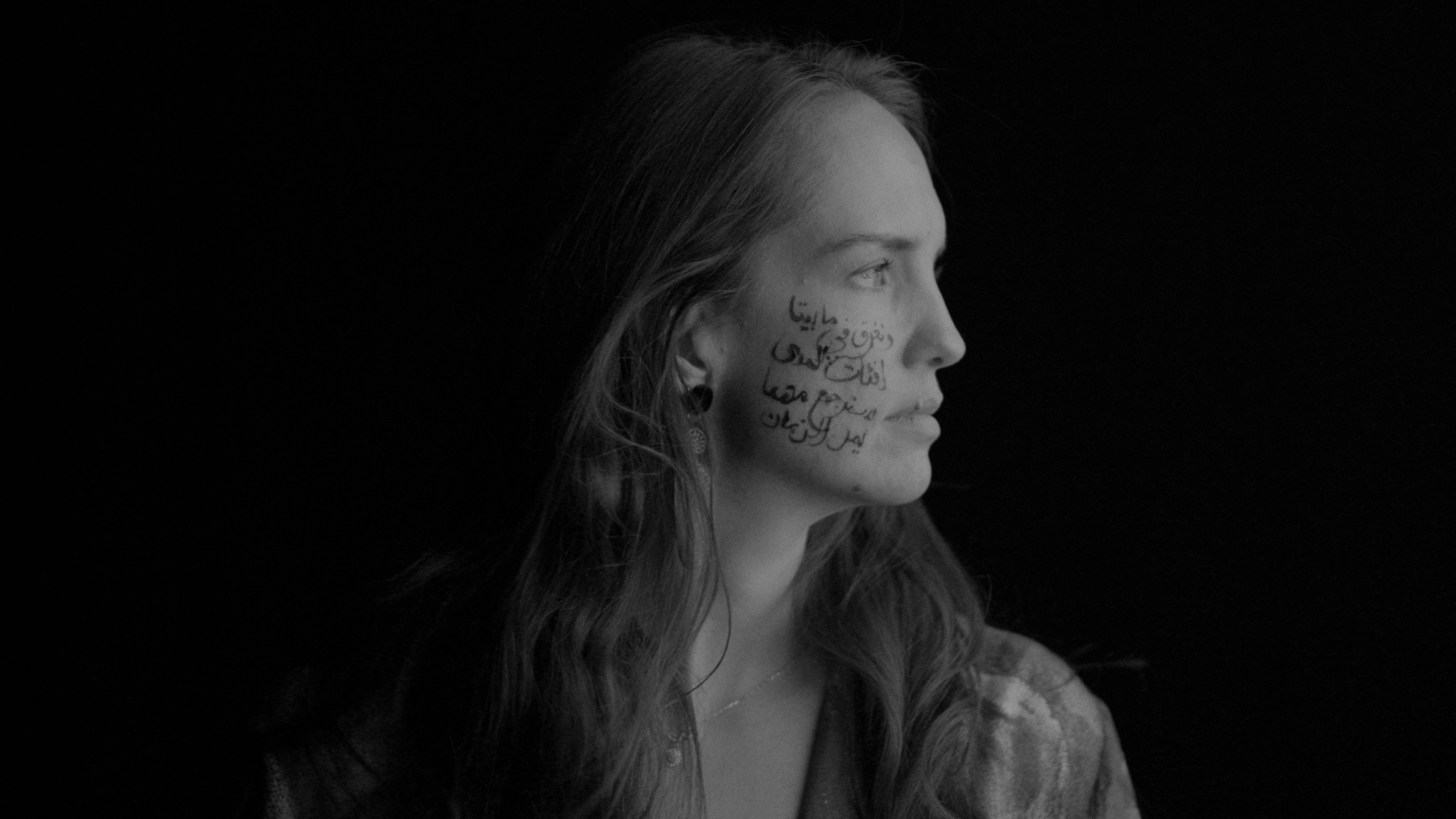 A Gumbaynggirr woman with Arabic text drawn on her right cheek.
