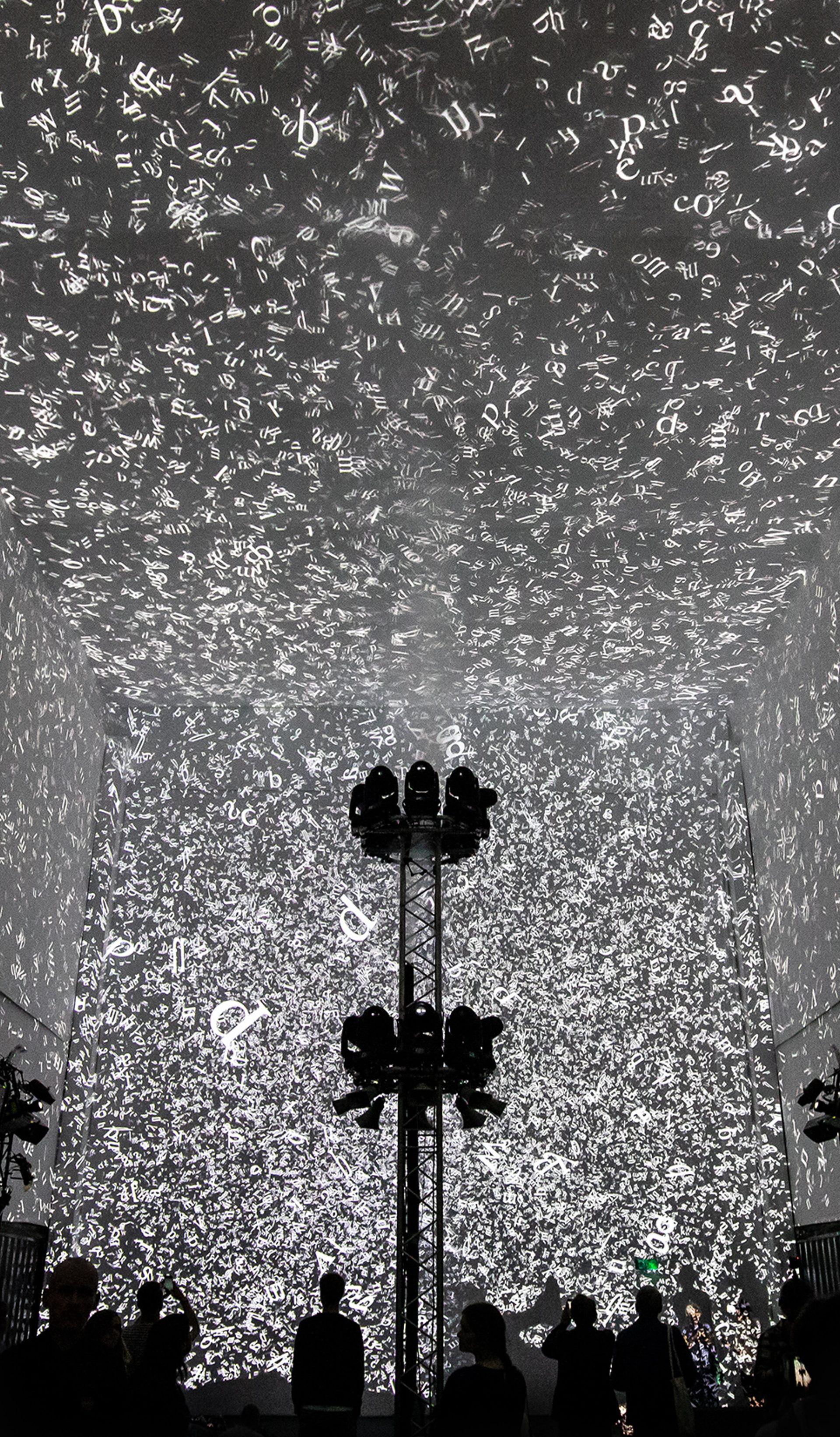 Silhouettes of 3 people walking in front of the Cloud Display, a wall of smoke simulating cloud vapour