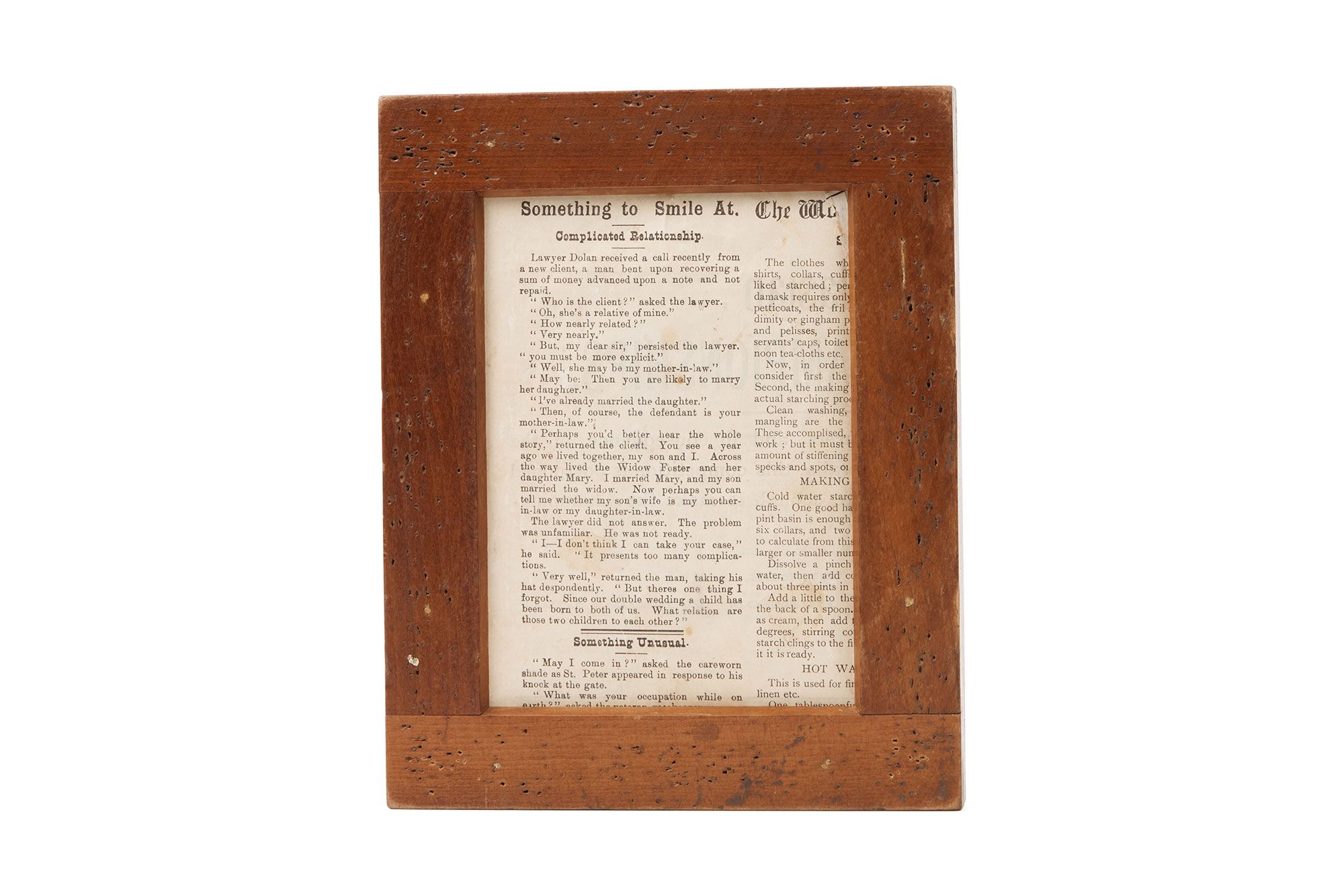 A wooden frame with newsprint inside. Title text states ‘Something to Smile At.’