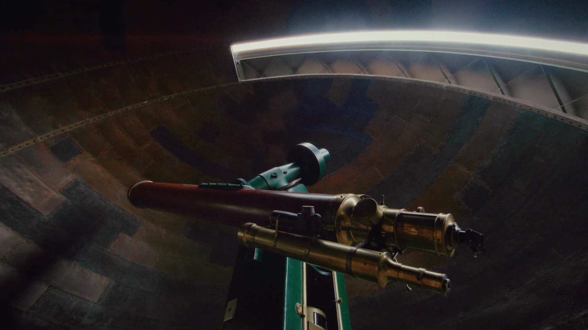 View of a telescope within a dome, from below.