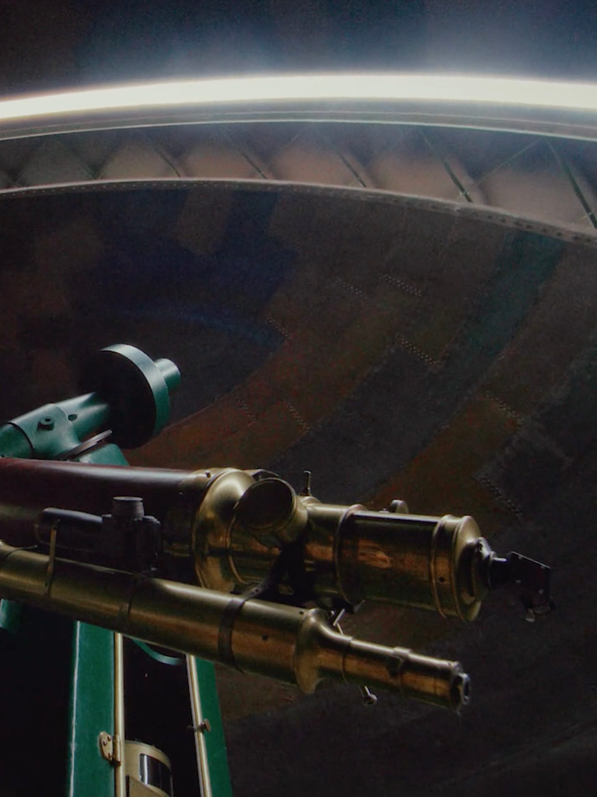 View of a telescope within a dome, from below.