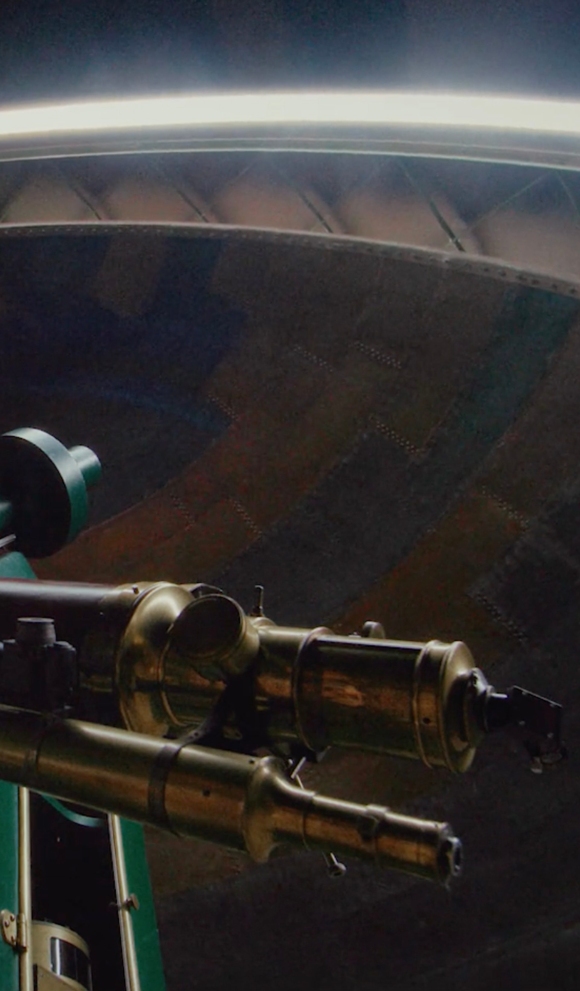 View of a telescope within a dome, from below.