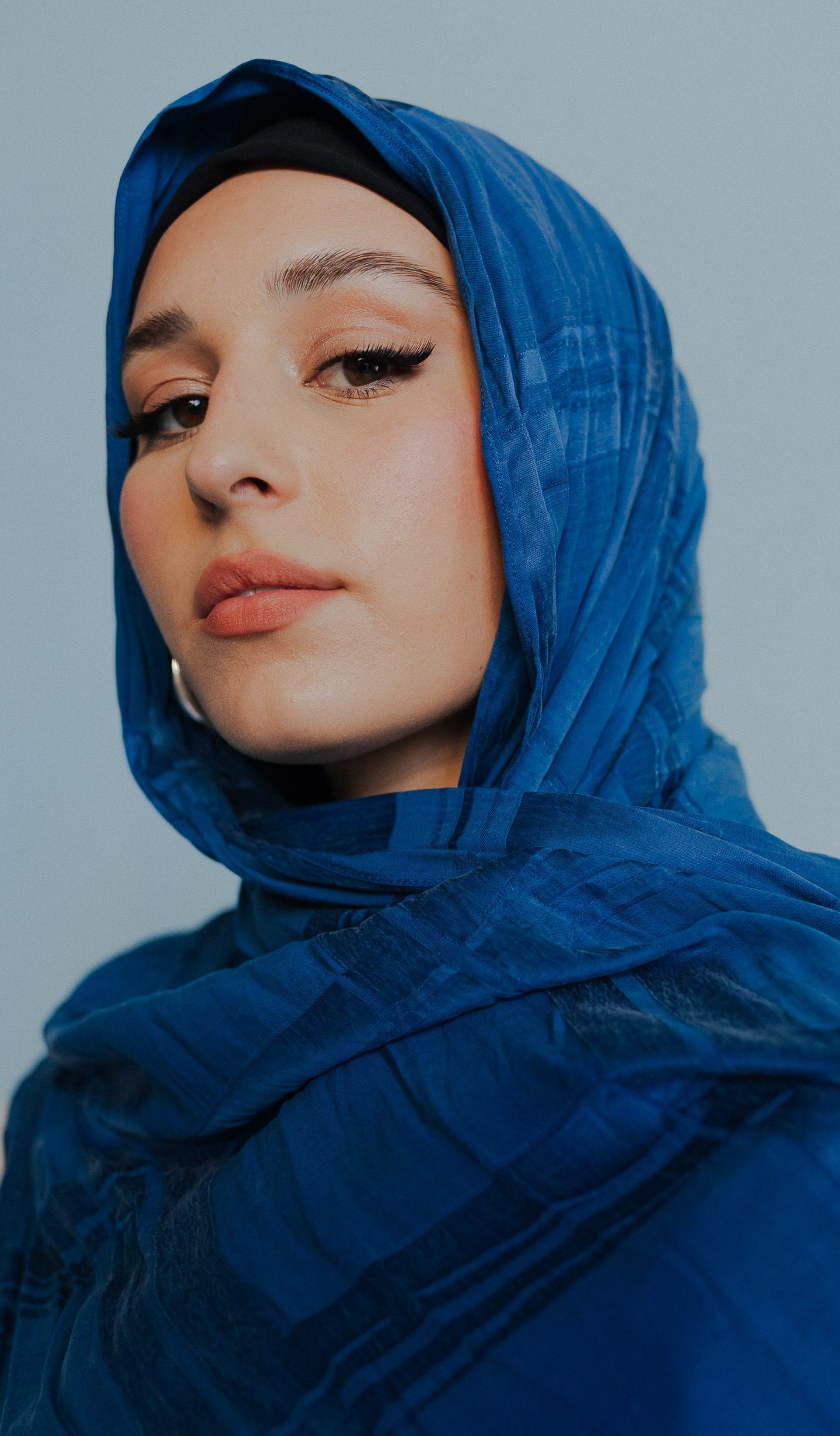 Portrait of a woman wearing a blue Hijab headscarf.
