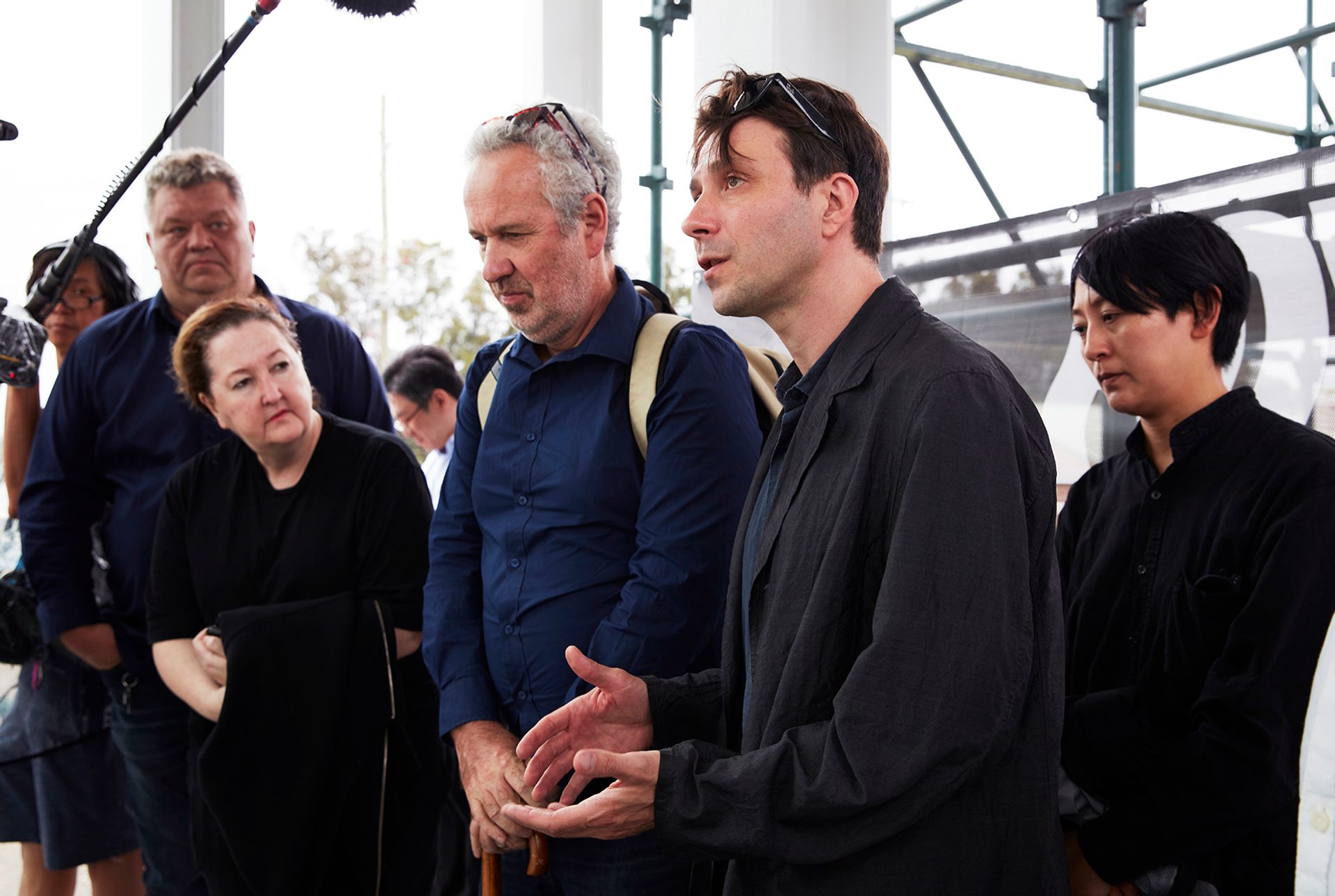 person talking under a boom mic surrounded by people