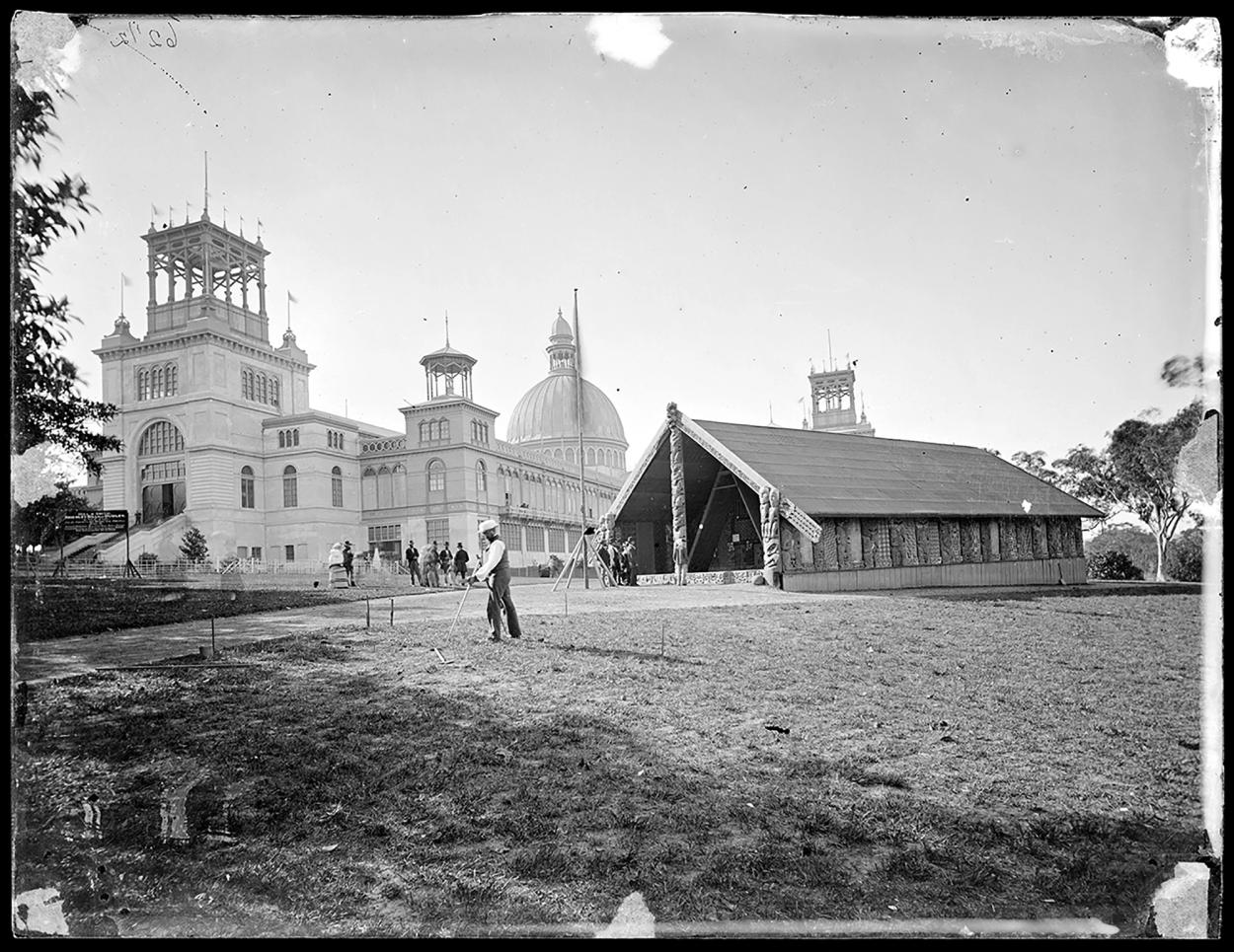 Black and white image of the Garden Palace from a distance featuring a tent and man in the foreground