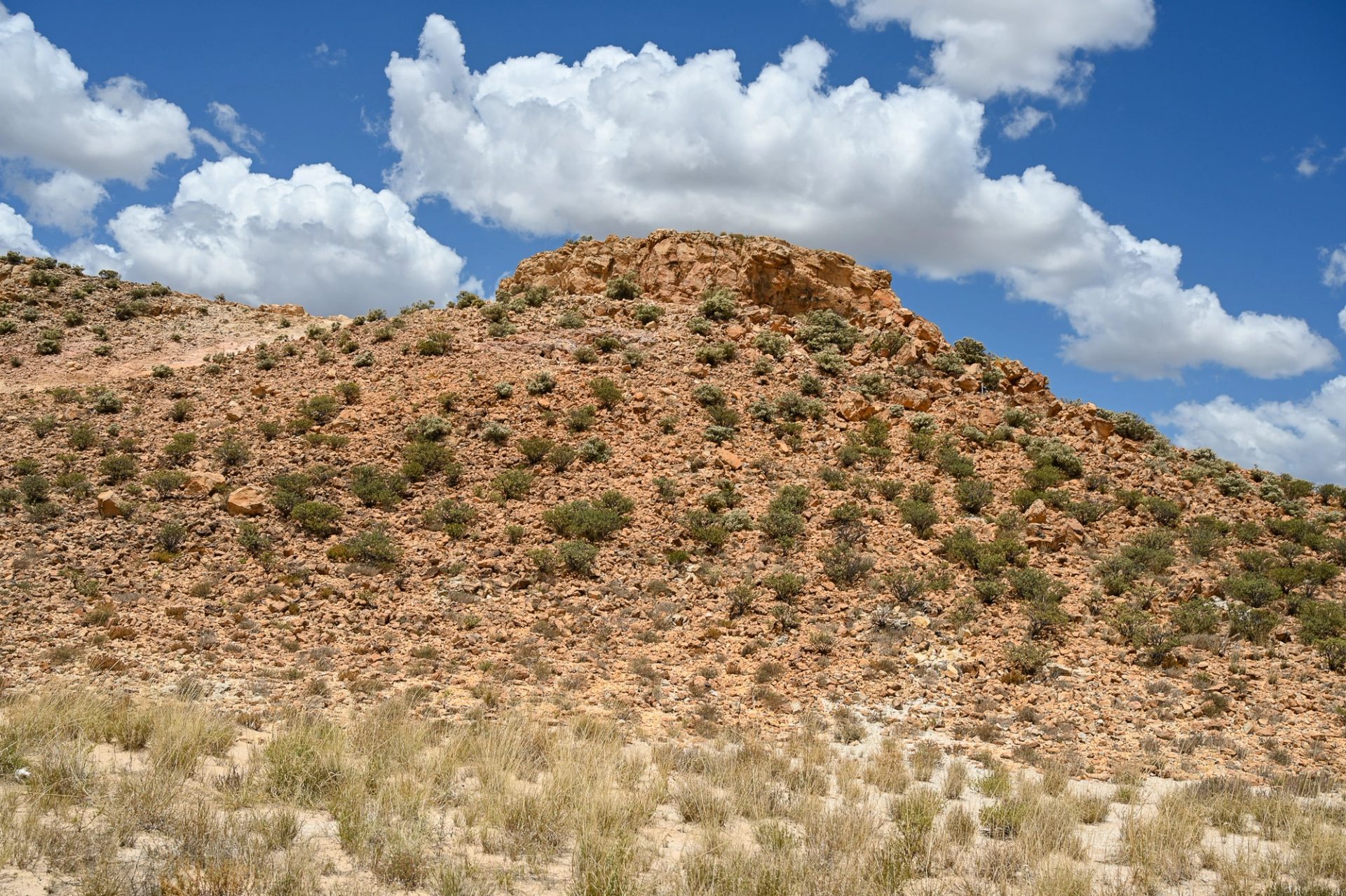 Dry, rocky landscape with a blue, cloudy sky above.