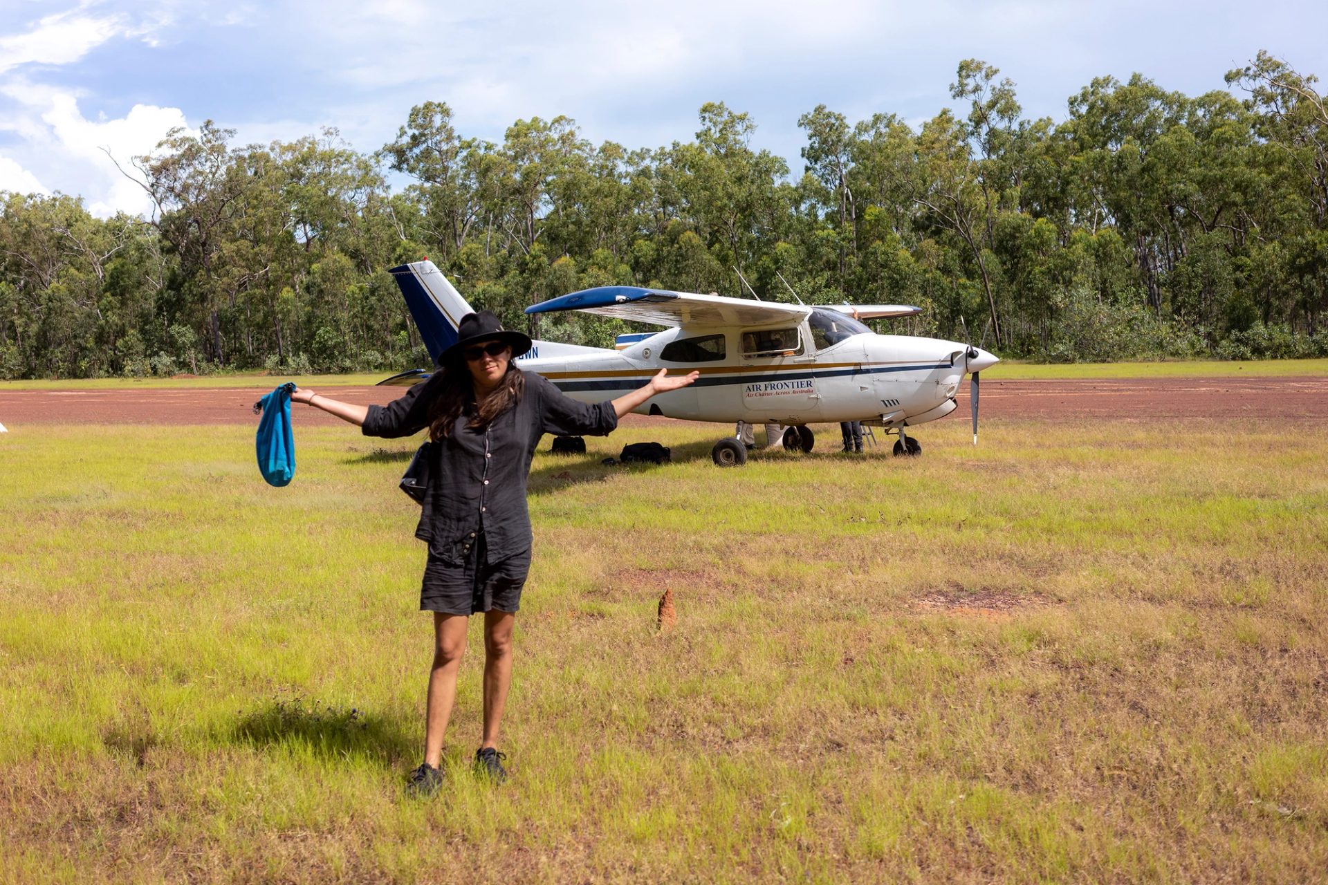 A woman stands in front of a small passenger plane.