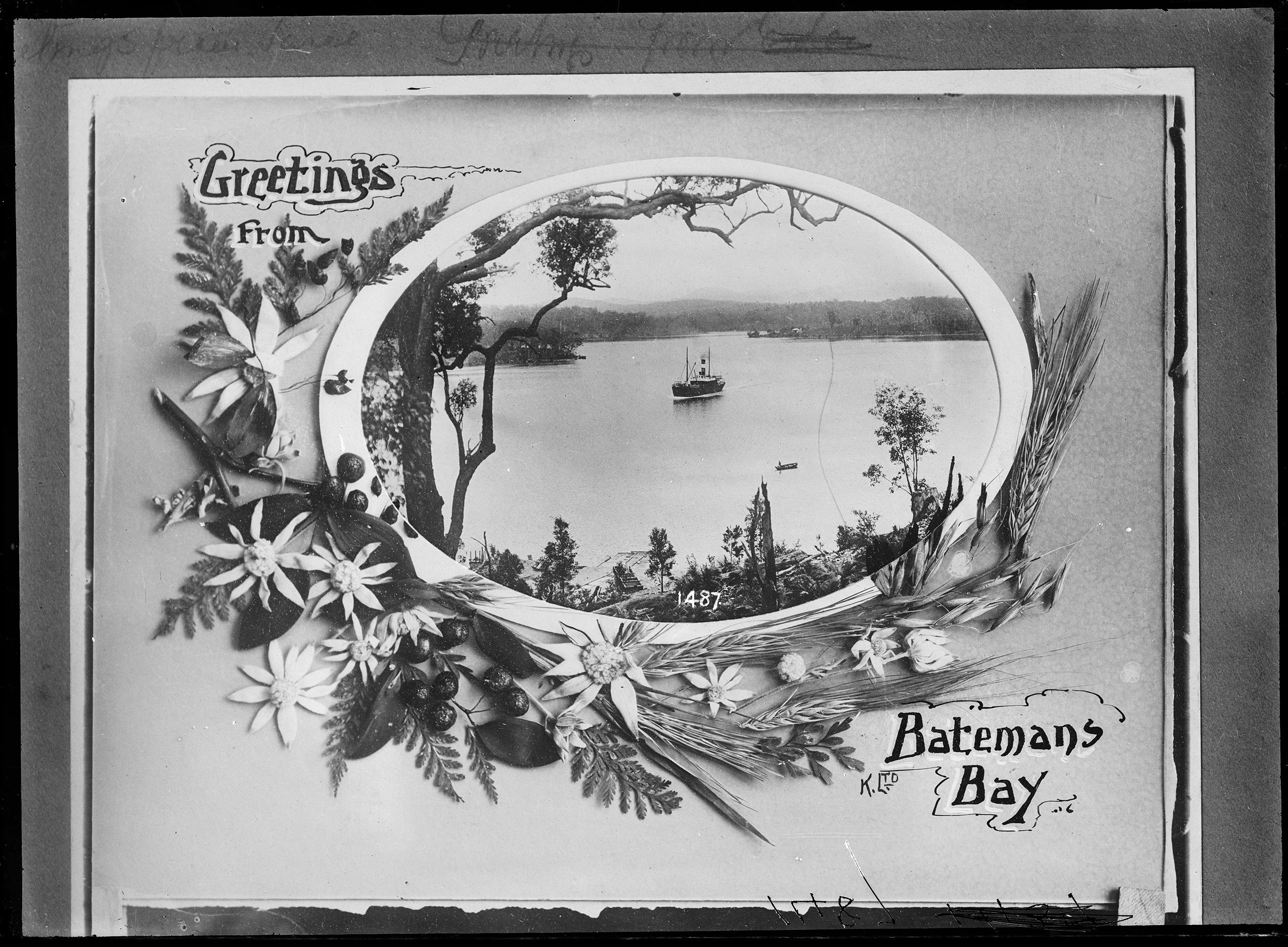 A ship and canoe in a bay surrounded by trees. The image is bordered by an oval, dried flowers and leaves. At the top left is text ‘Greetings From’.