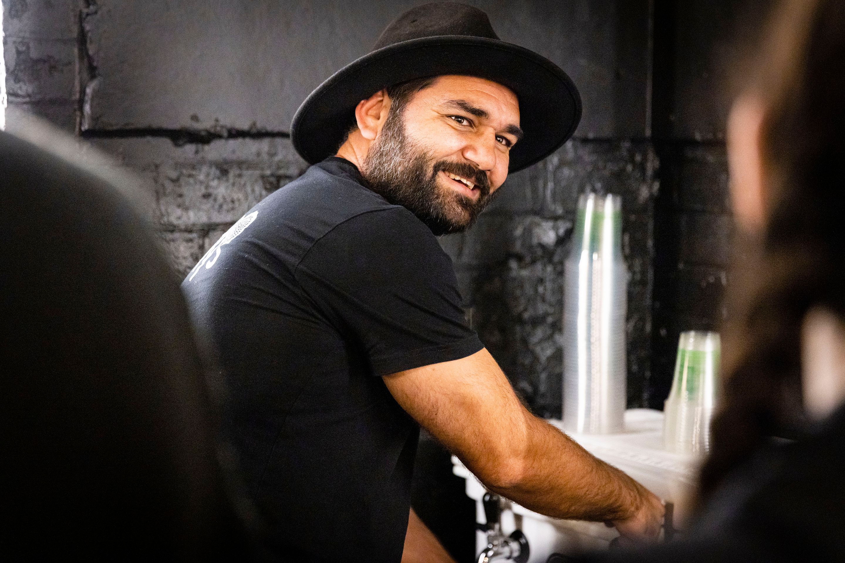Man smiles towards camera while pouring beer