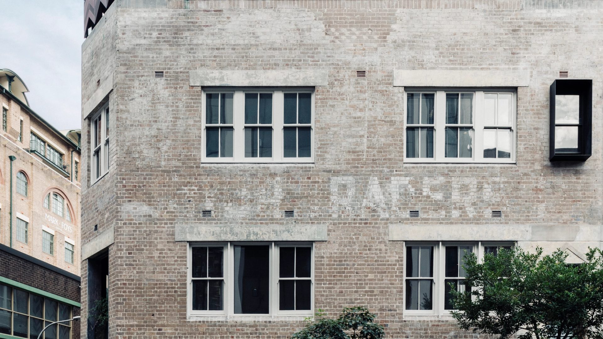 A blurry bicycle rider rides past a building in the foreground.