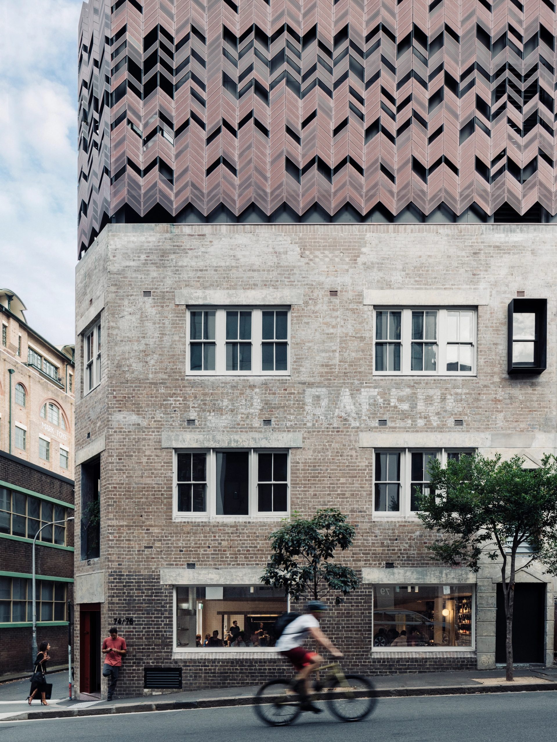 A blurry bicycle rider rides past a building in the foreground.