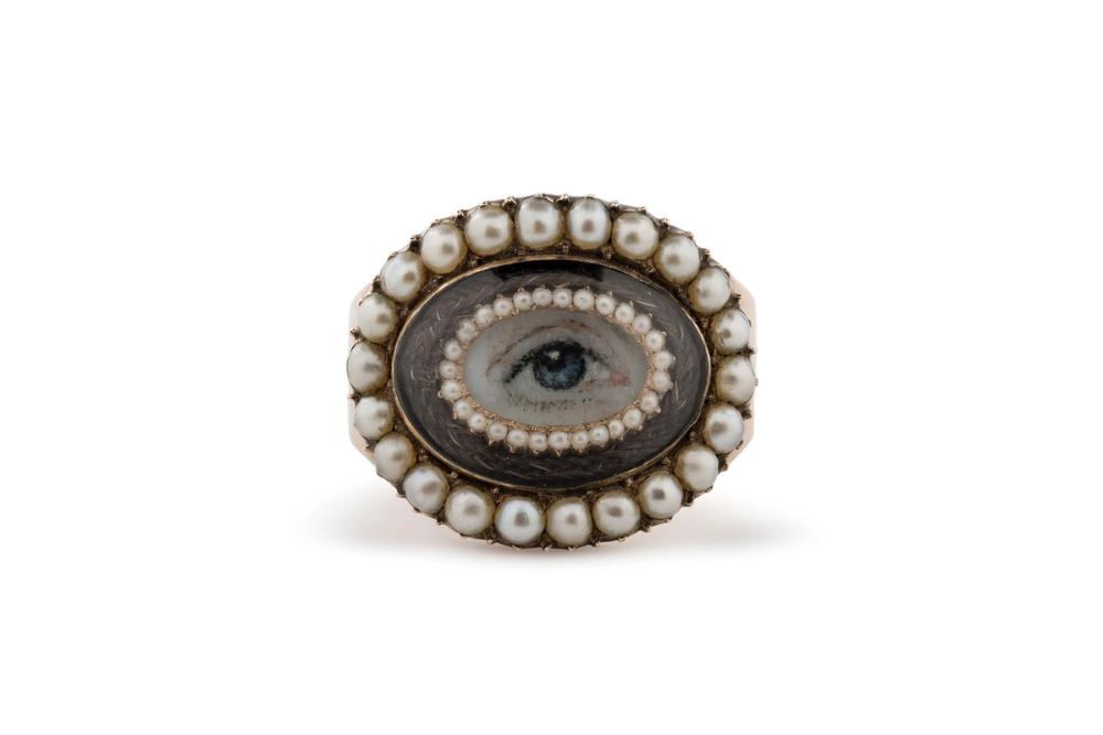 A gold ring set with a miniature painting of an eye with pearls around the edges.