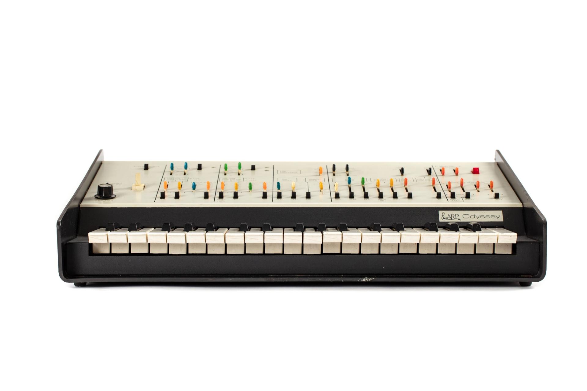 A duophonic synthesizer consisting of a three octave compass keyboard and control panel. The control panel is divided into six parallel sections. The sections include switches and controls to operate various functions. The body of the synthesizer is a single piece of moulded black plastic which bends up at sides to form sloping wings each side. At the rear of the instrument is a series of sockets, jacks and a mains lead.