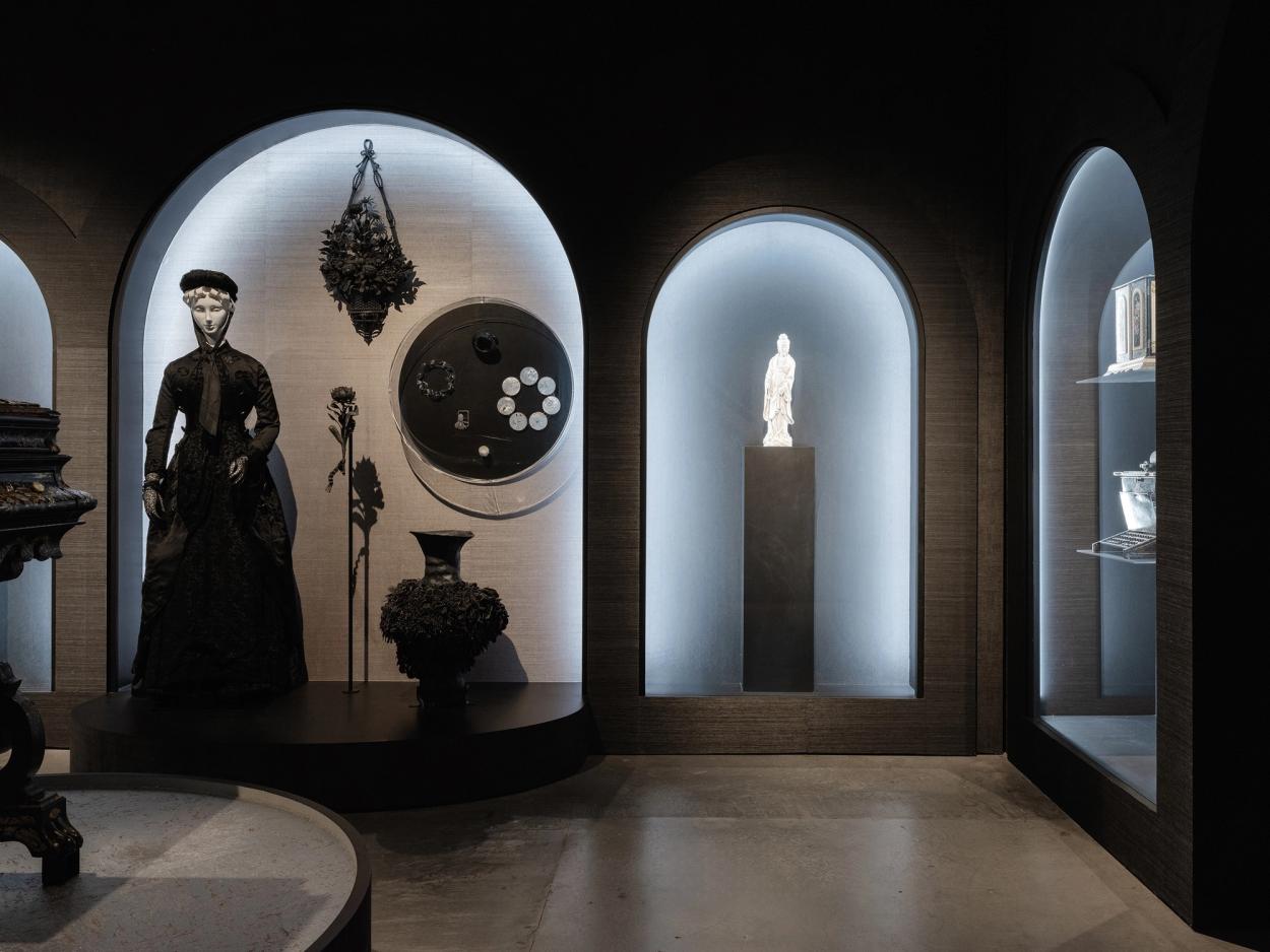 Dark, exhibition with arches for displayed objects.