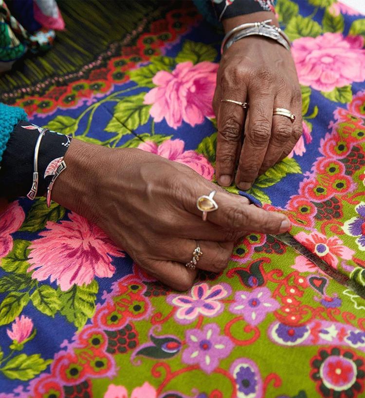 The hands of a brown woman touching a colour shirt with a floral pattern.