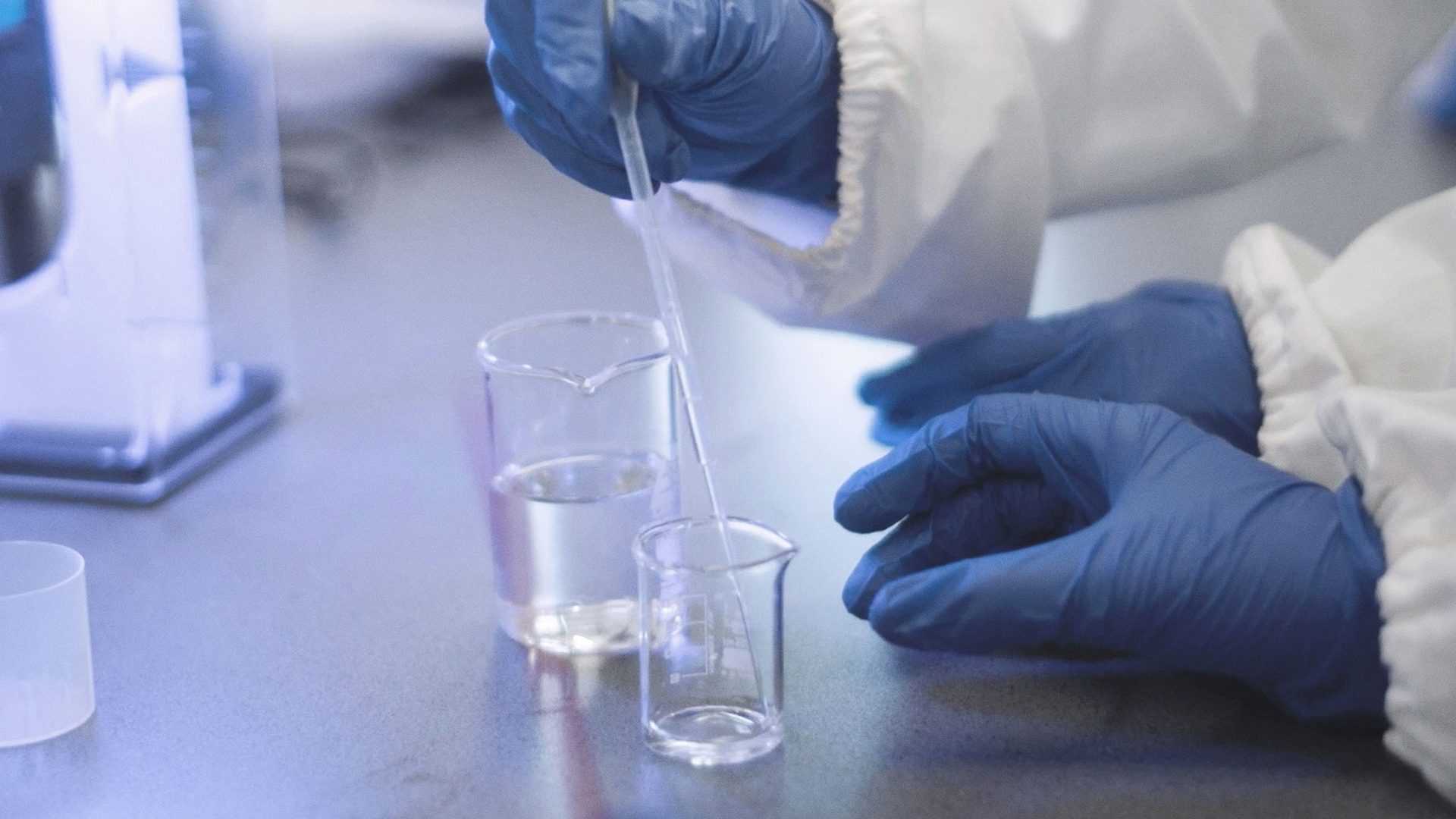 Scientist wearing blue gloves uses pipet during an experiment.