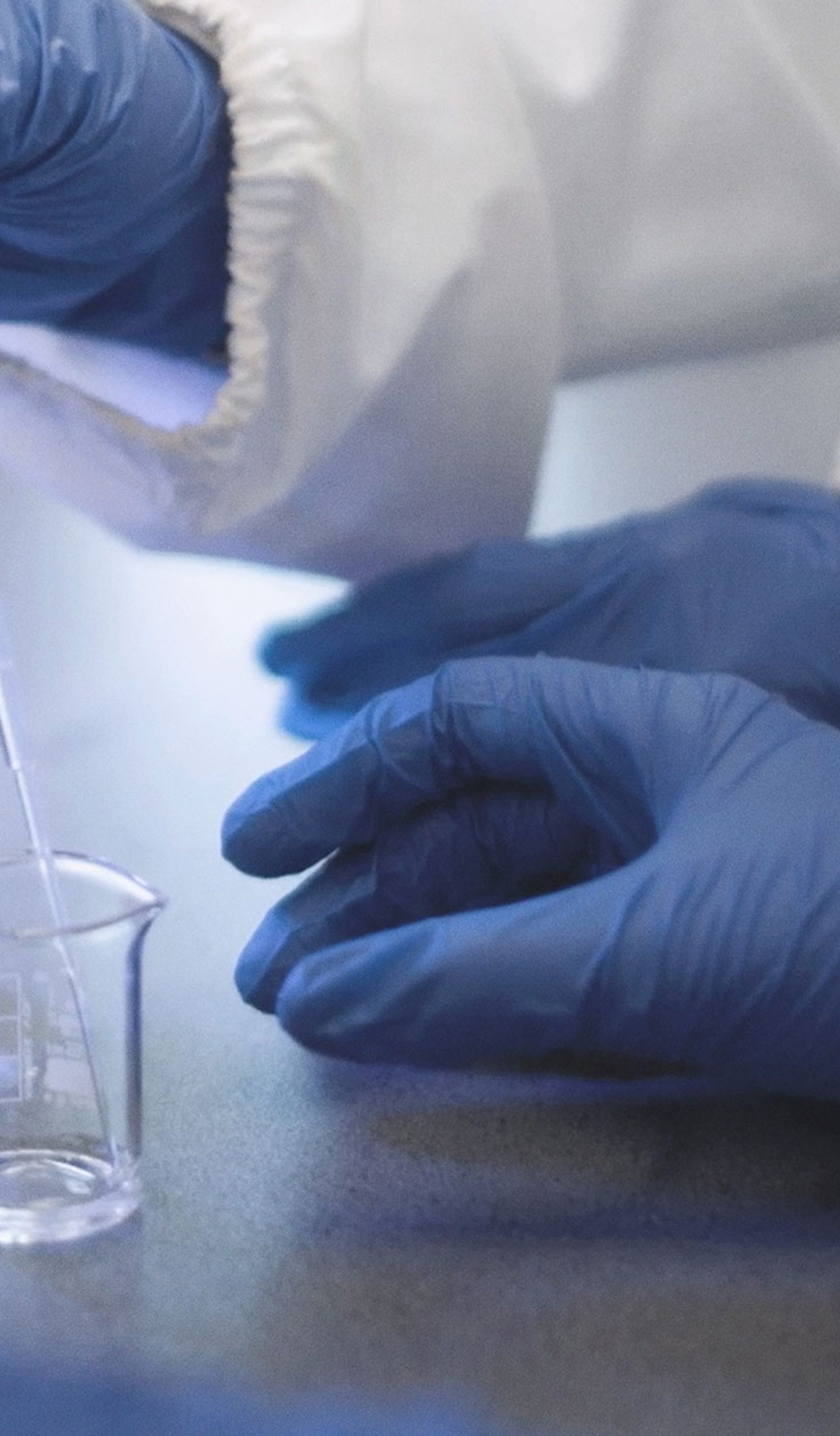 Scientist wearing blue gloves uses pipet during an experiment.