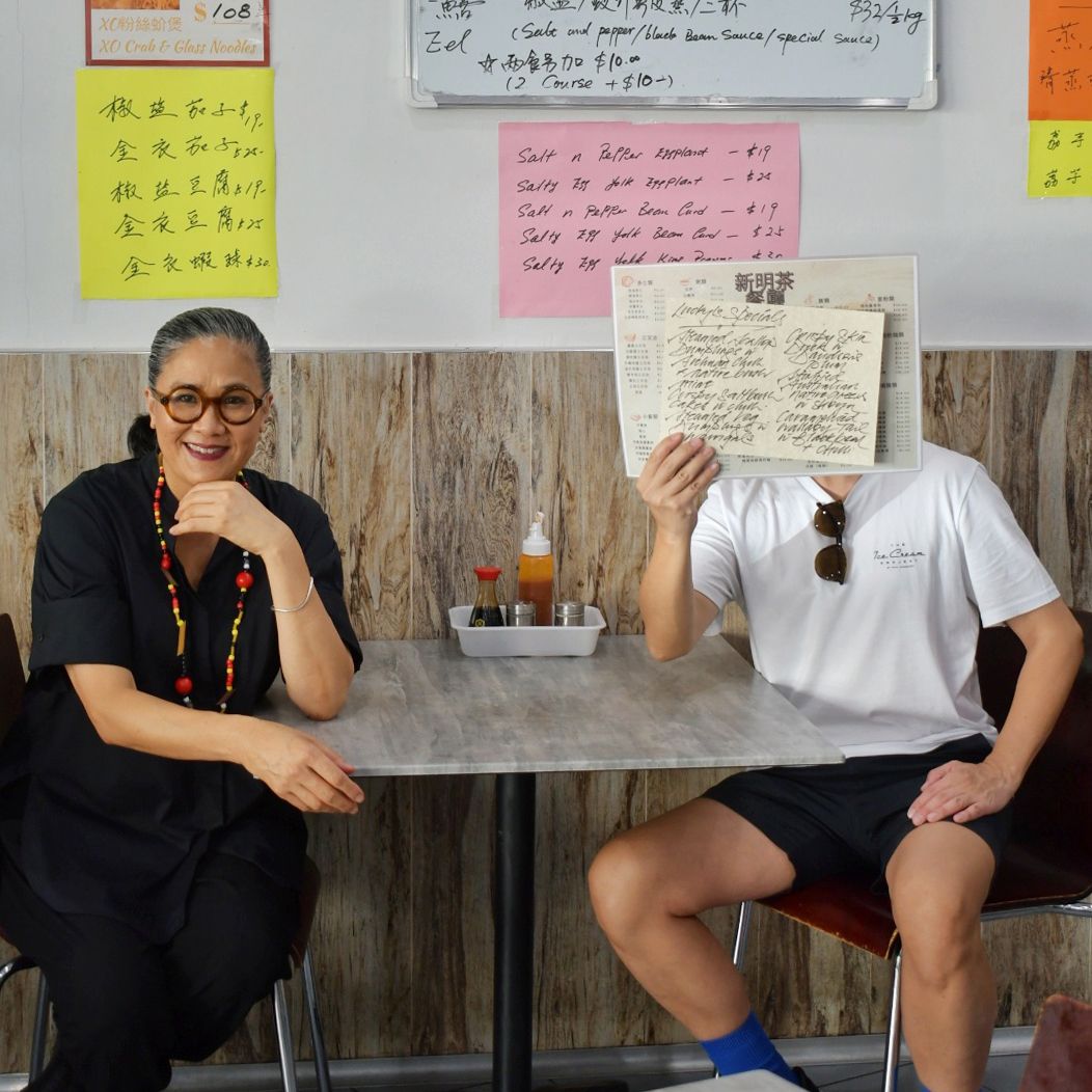 Two figures sit next to each other, across the table.