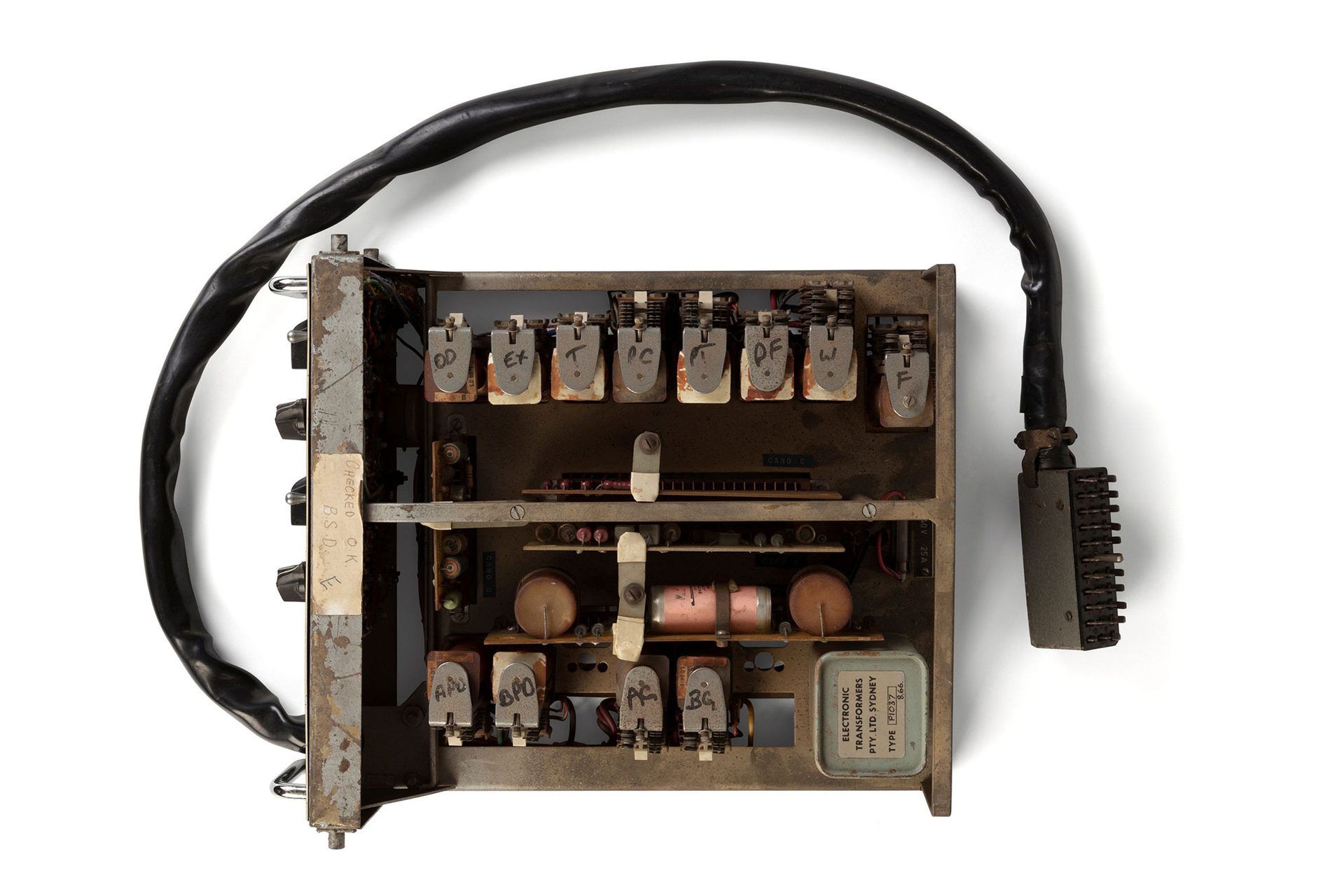 The PX-2 is a control housed in a metal rack designed to be secured in a traffic control box that you see by the side of the road near traffic control lights. It has relay-logic electronic circuits that control the duration and sequence of light signal events that occur at a pedestrian crossing. There is a black painted metal plate and dials at the front of the unit that permit the adjustment of times dependent upon the size of the intersection at which it is to be installed. There is a large multi-core cable which runs from the unit to a connector.