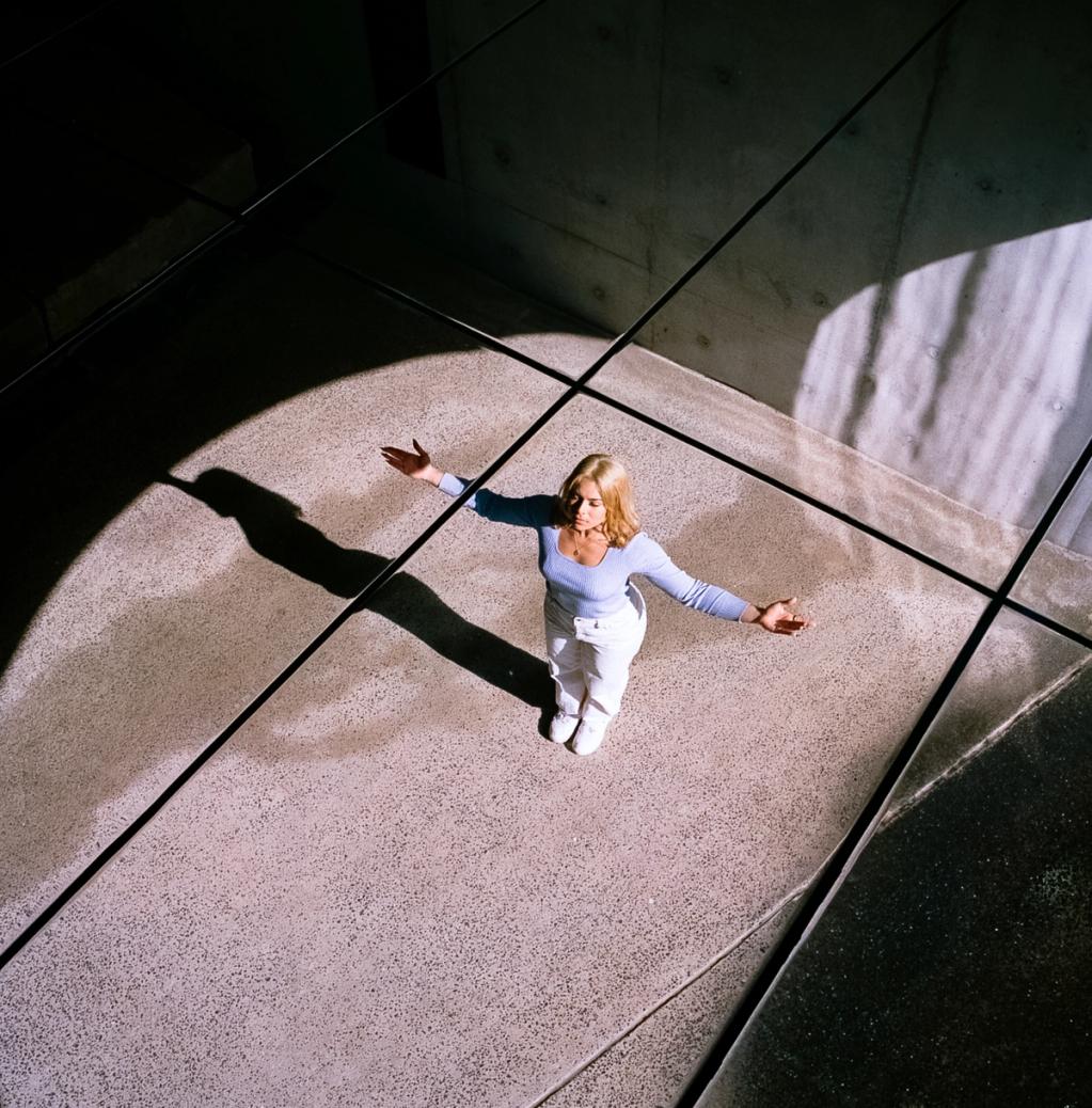 View of woman from above on a bare concrete floor, basking in the sunlight