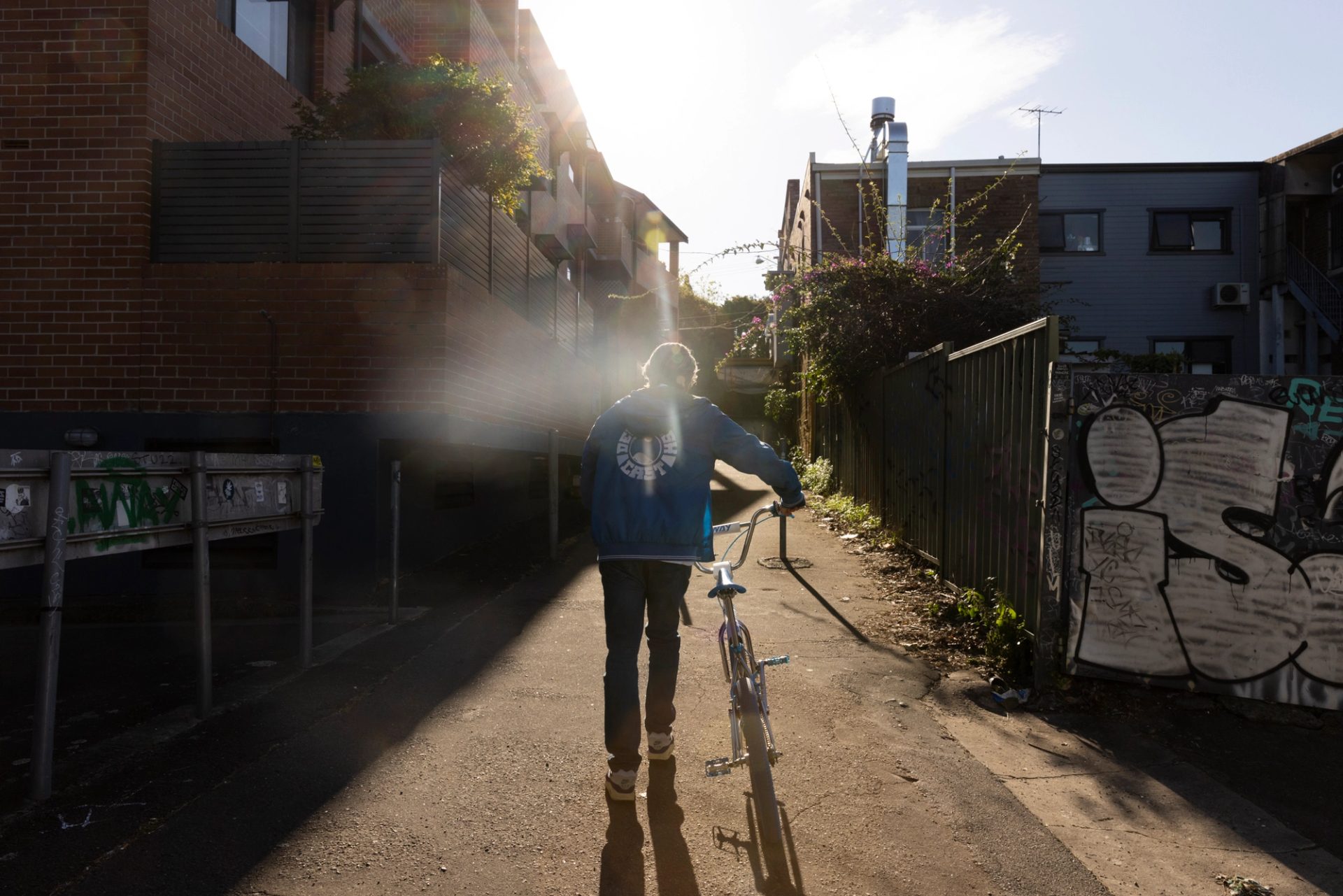 Man walking into alleyway with bike.