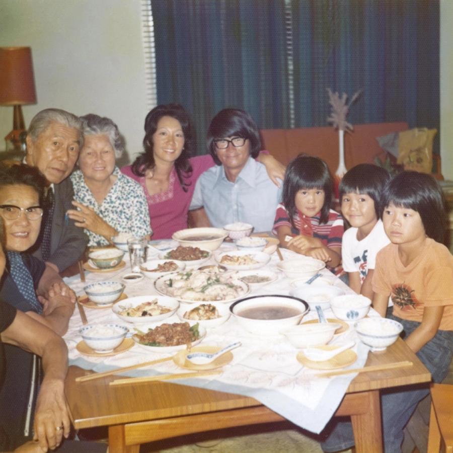 A photo from the 1970s of eight members of Kylie Kwong’s extended family including two grandparents sitting at a dining table, sharing a meal.