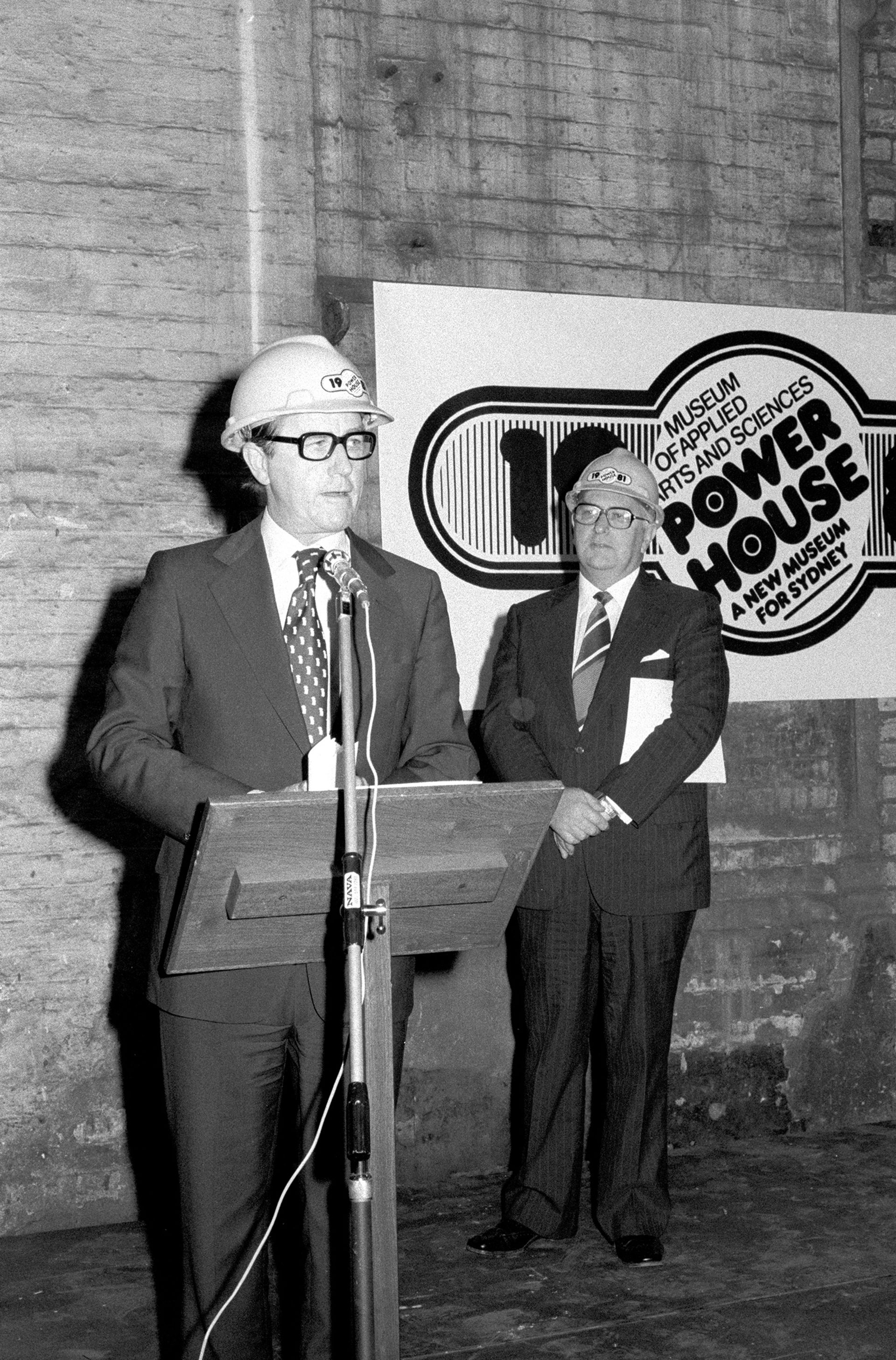 humans wearing hard hats at the microphone