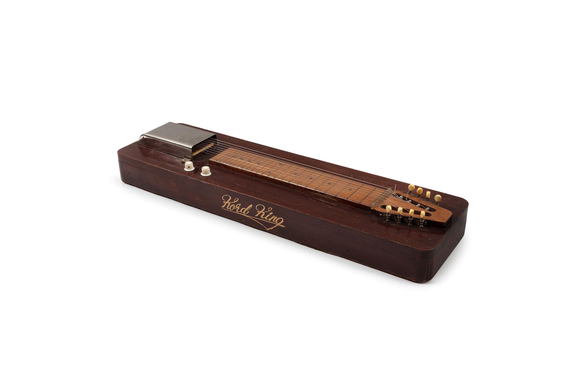 A Wooden board with the guitar neck with eight strings laid flat against it.