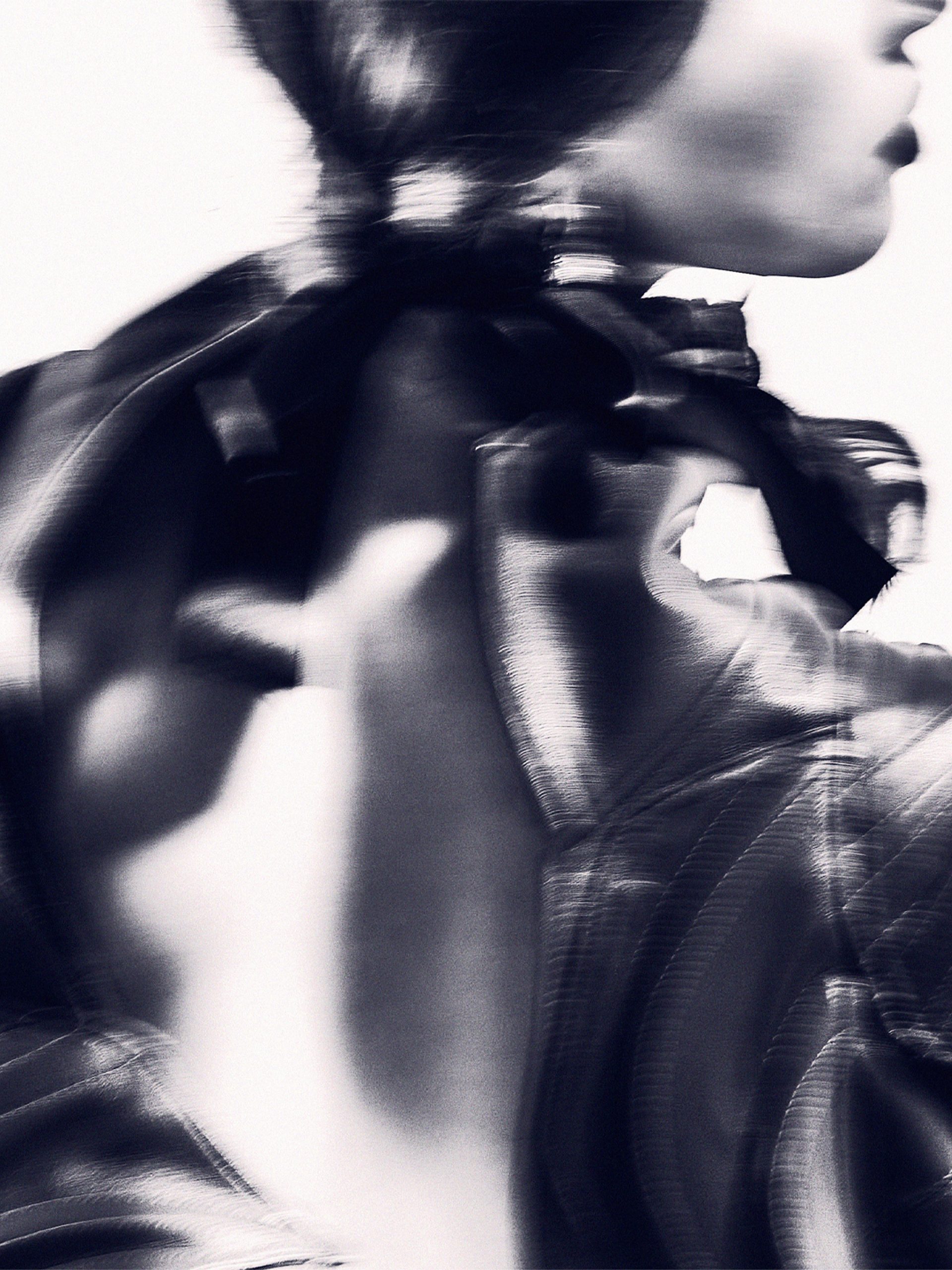 An abstract high contrast image of the back of a model, wearing a shiny leather jacket.