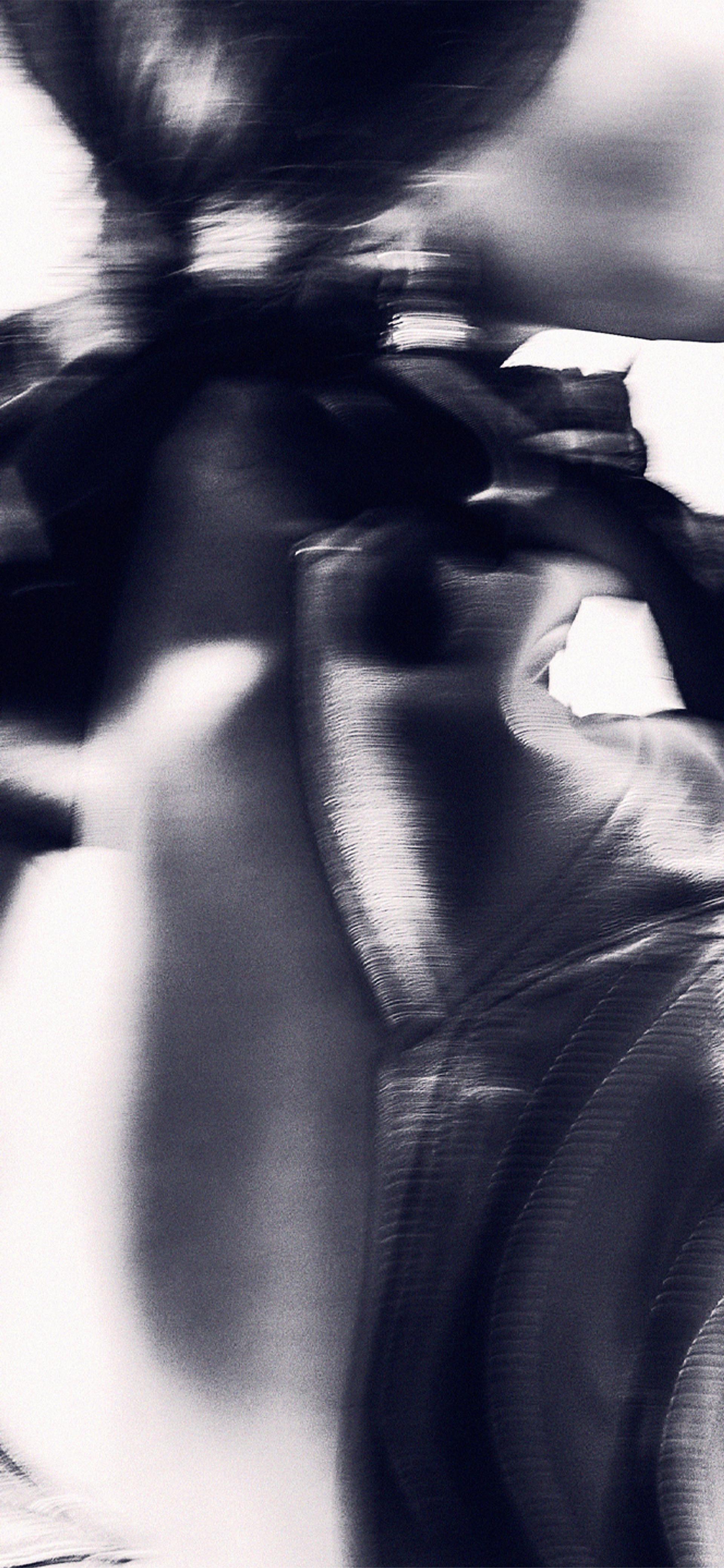 An abstract high contrast image of the back of a model, wearing a shiny leather jacket.