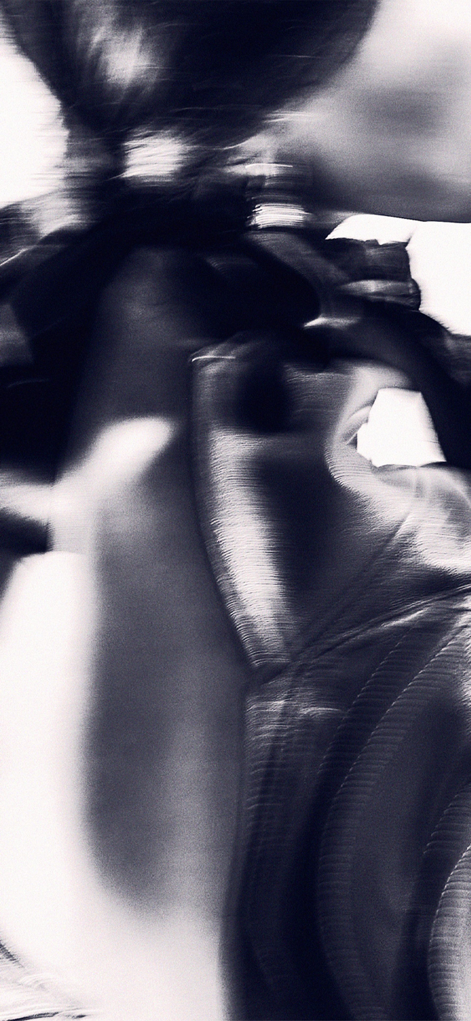 An abstract high contrast image of the back of a model, wearing a shiny leather jacket.