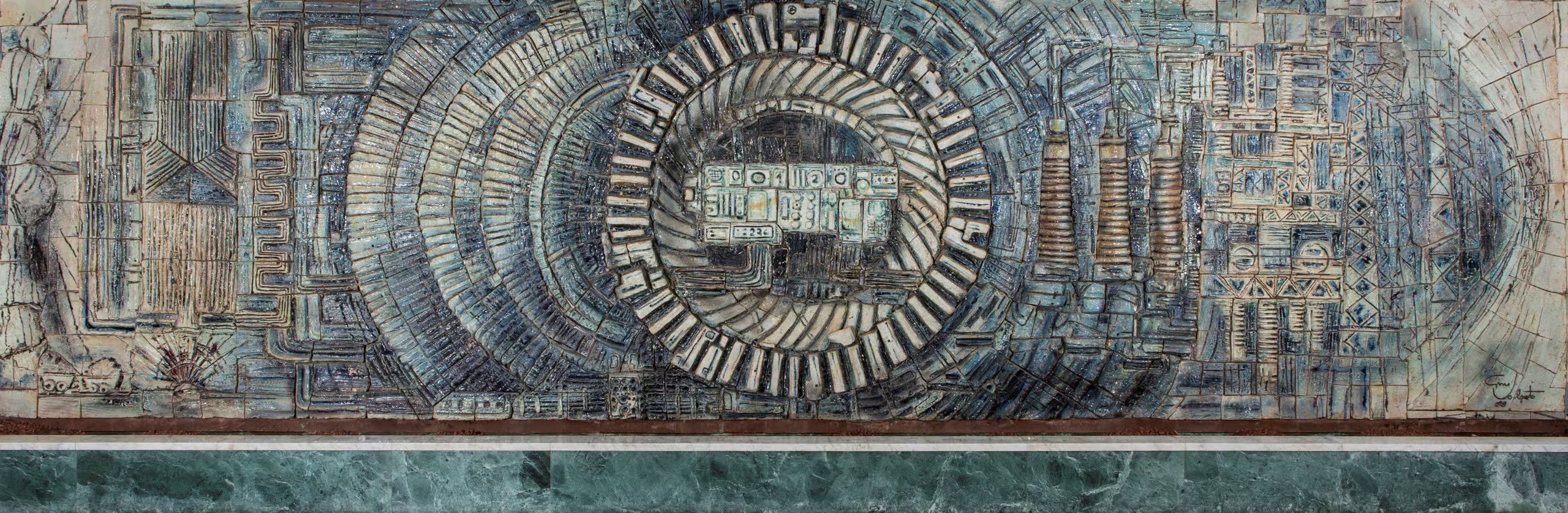 Mural consisting of 792 handmade, glazed terracotta tiles. The design is in relief, overall a stylised depiction of electrical generation, transmission and control. Off-white and blue glazes are used, the former mostly for the designs in relief and the latter for the background plane. The most prominent central portion of the mural is dominated by the nested, circular design depicting the poles and armatures of the power station generator, as well as stylised control panels.