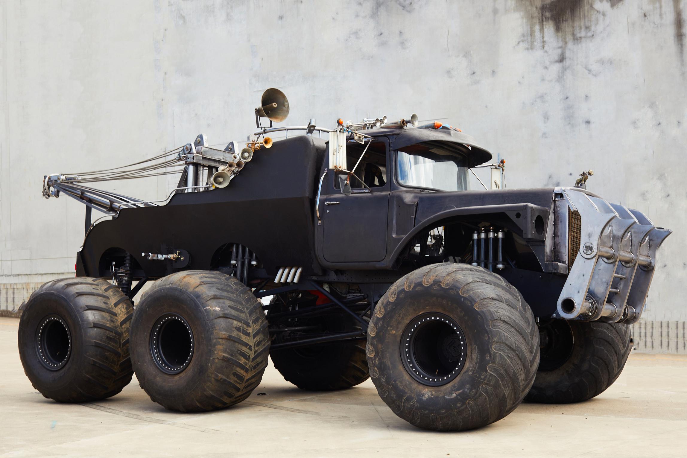 Black monster truck with big wheels and horns atop.