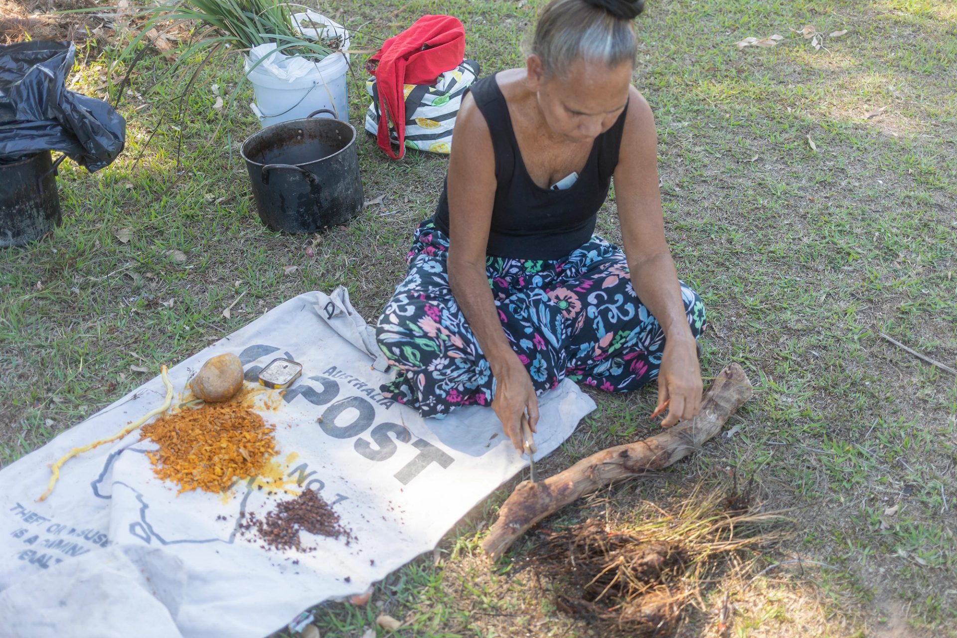 A woman sits on the grass with her legs crossed.