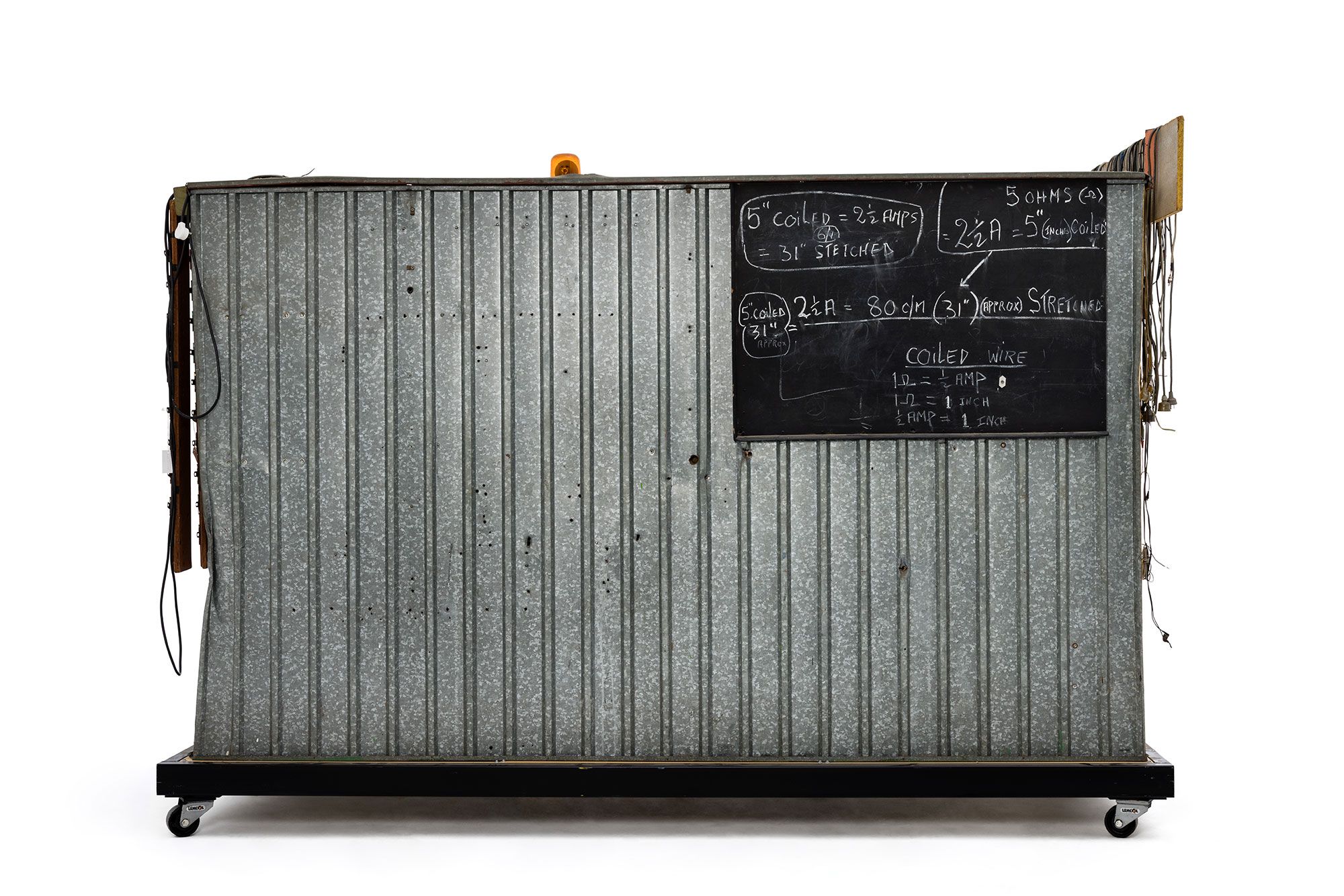 Green and yellow metal 'garden' shed containing elaborate electronic systems built into the interior. Inside the shed is a compartment which contains a seat where the user can sit and be suffused with radio waves produced by the electronic system.