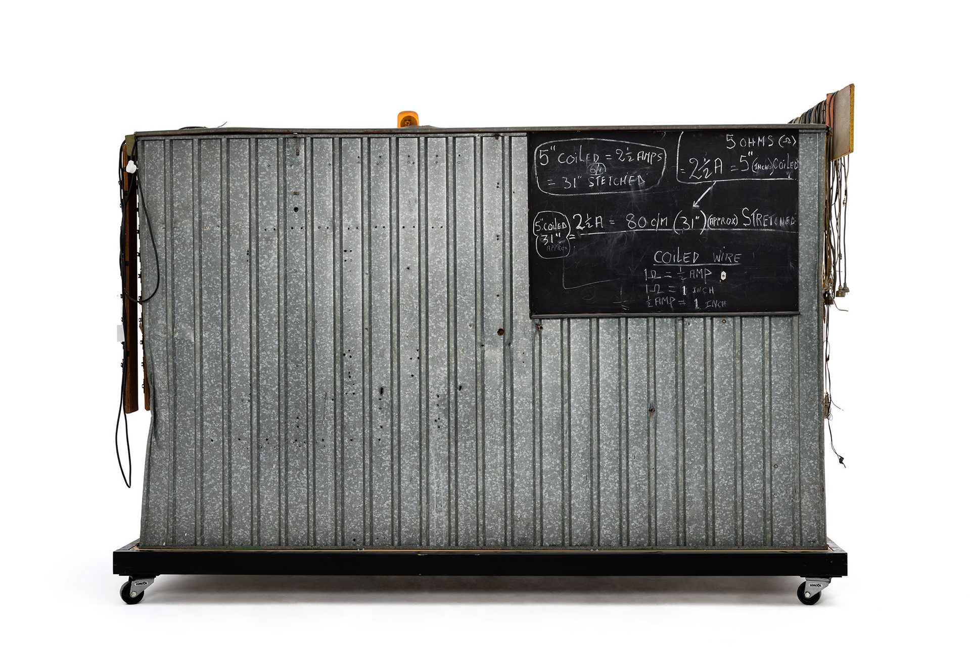 Green and yellow metal 'garden' shed containing elaborate electronic systems built into the interior. Inside the shed is a compartment which contains a seat where the user can sit and be suffused with radio waves produced by the electronic system.