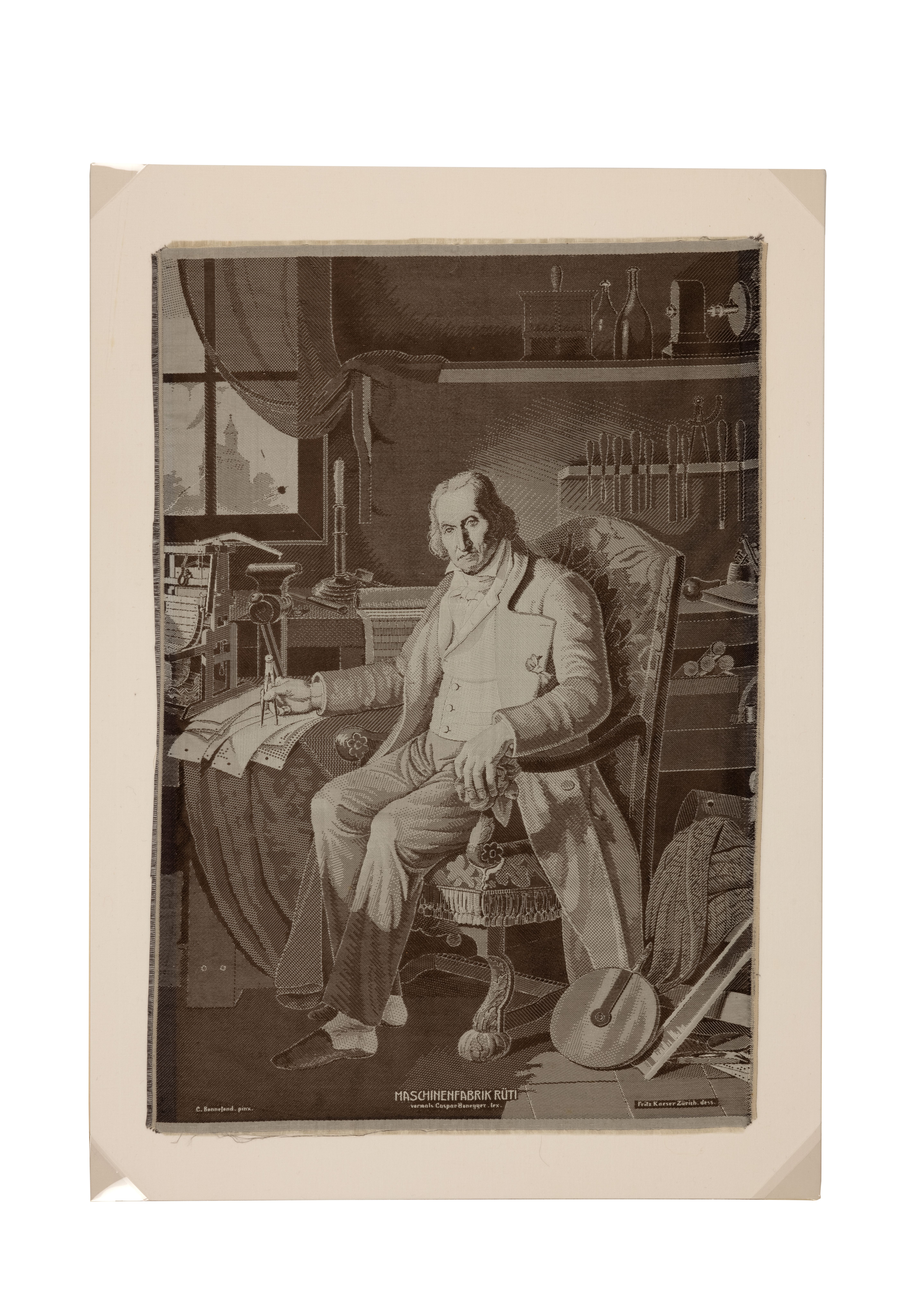 The monochrome portrait of a man sitting in a high-backed patterned arm chair next to a table where he is holding what appears to be a compass over some cards with holes in them - ie punched cards. Behind the chair tools can be seen in a rack on the wall, and on the bench below, a book and other scattered items. Next to the punched cards there is a small scale model of a loom, behind that, on the bench, a vice. There is a window on the left side of the image with a see-through curtain, the vague image of a church spire. Next to the chair on the floor is a pile of fabric and a wheel perhaps from a pulley. The subject is Joseph Marie Jacquard and the process of construction is weaving.