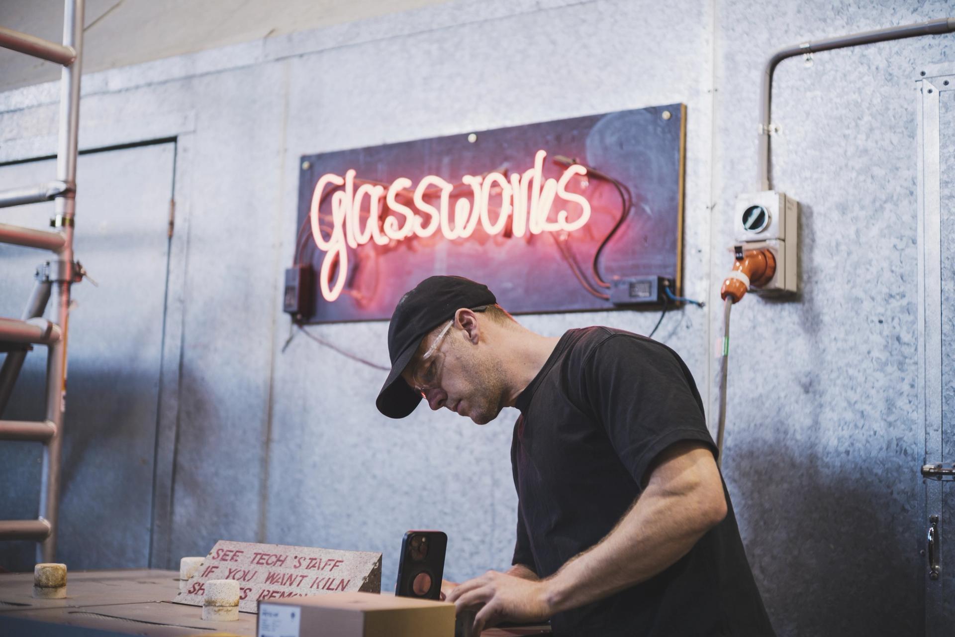 A man works with glass at a glass factory.