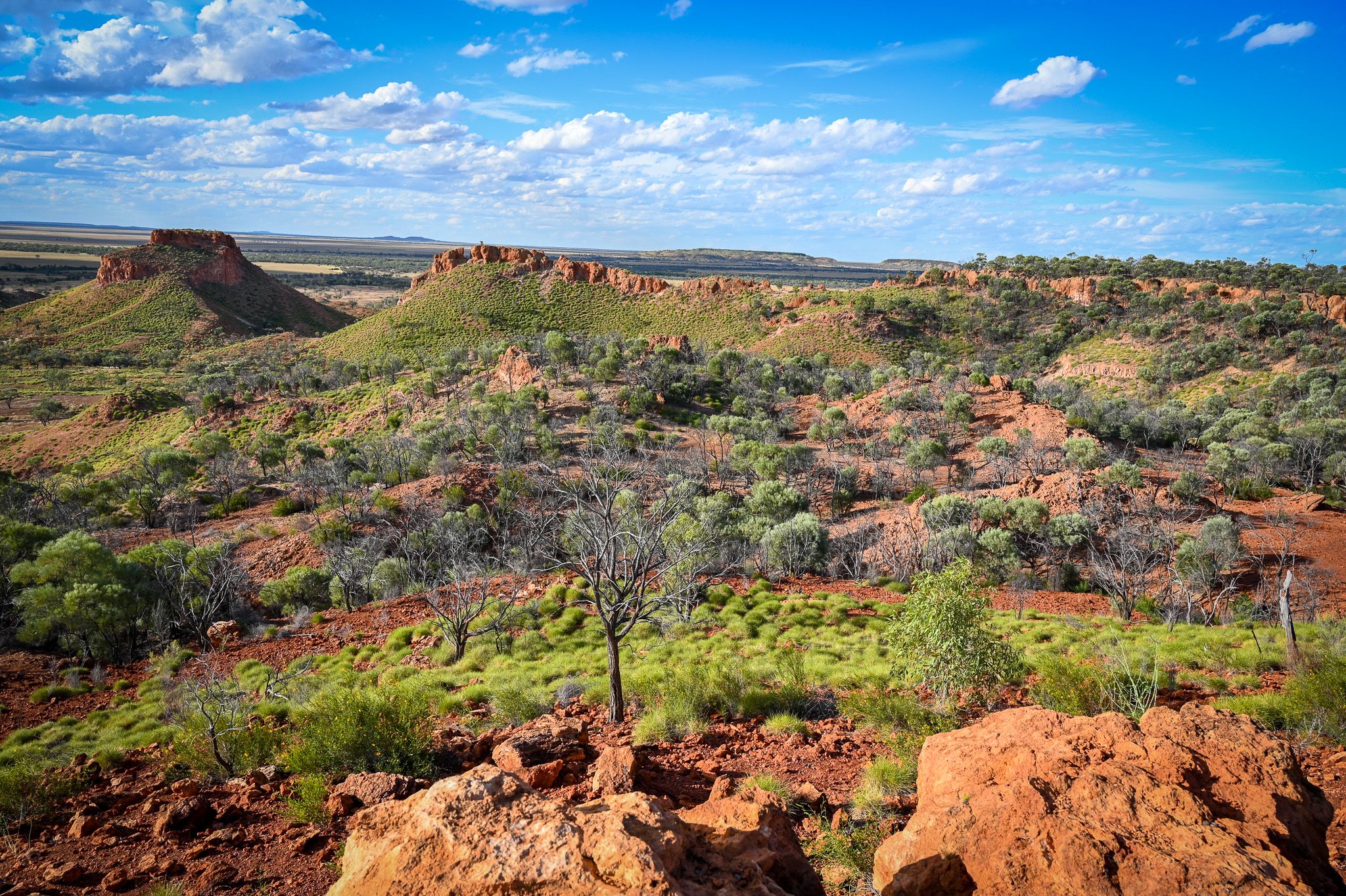 Guwa Koa Country landscape. Green and red hills below a blue sky.