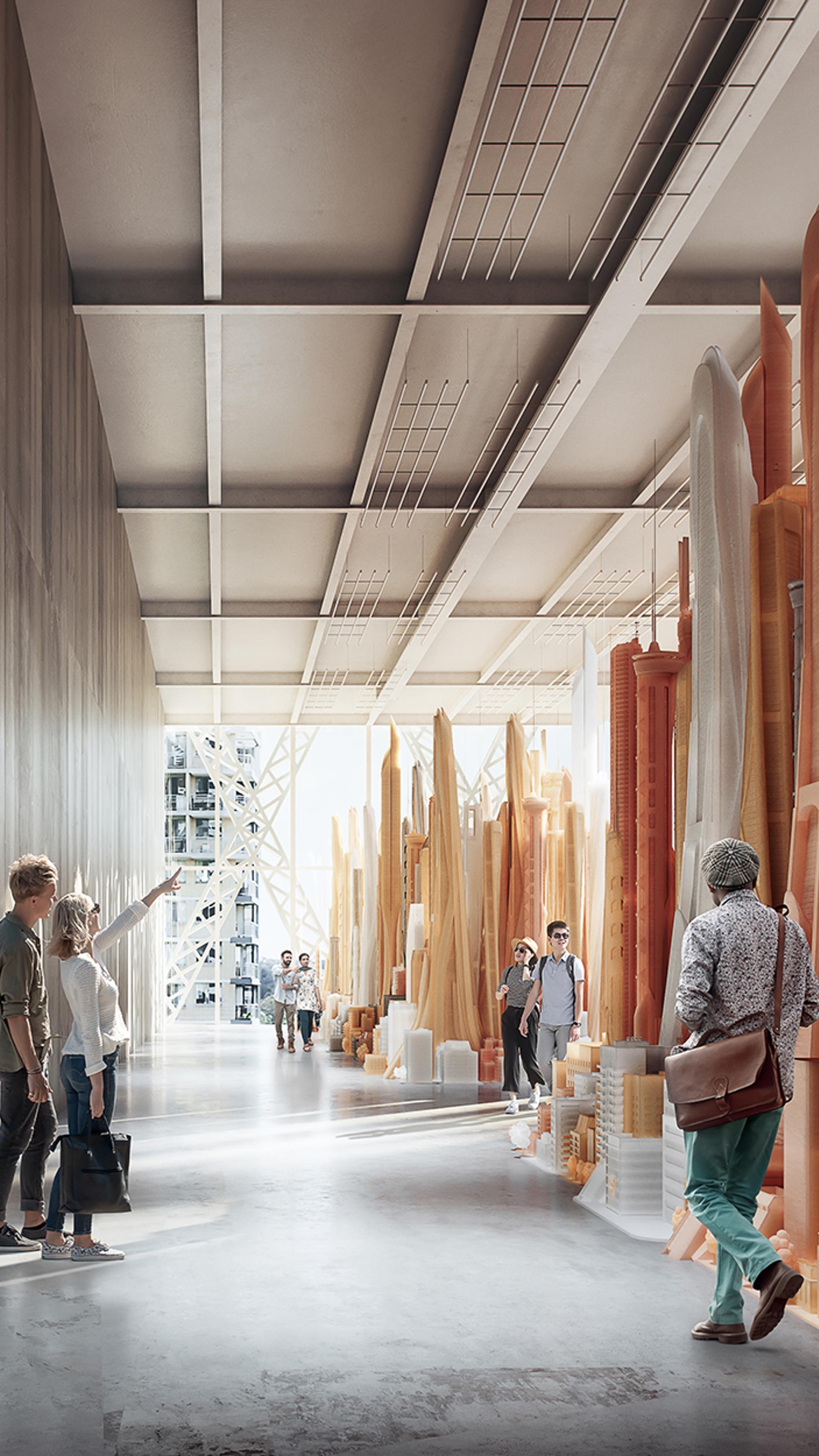 A large gallery with a high ceiling, concrete walls and floor. There are people in the gallery looking at large orange sculptures.