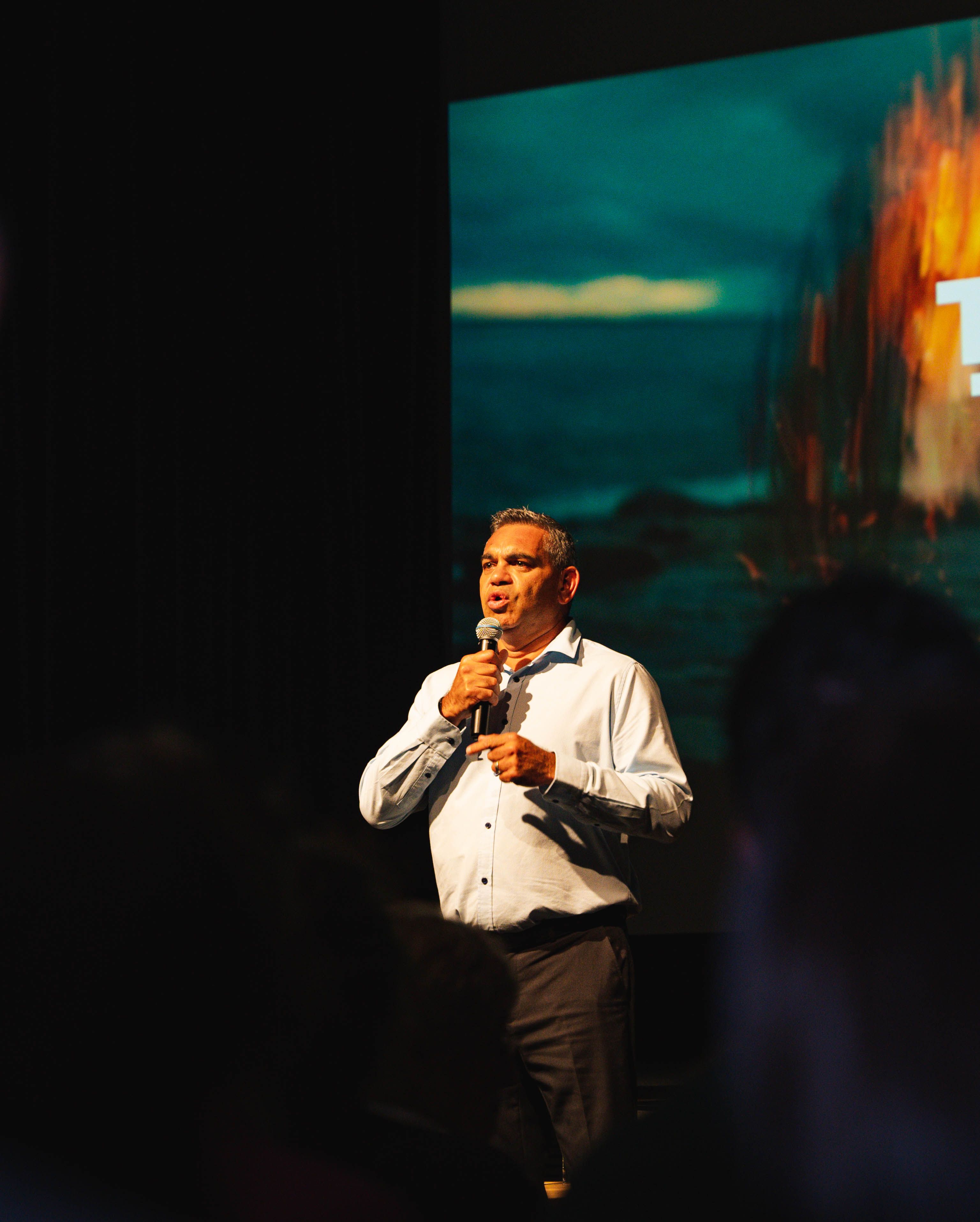 A man is standing on a stage and holding a microphone.
