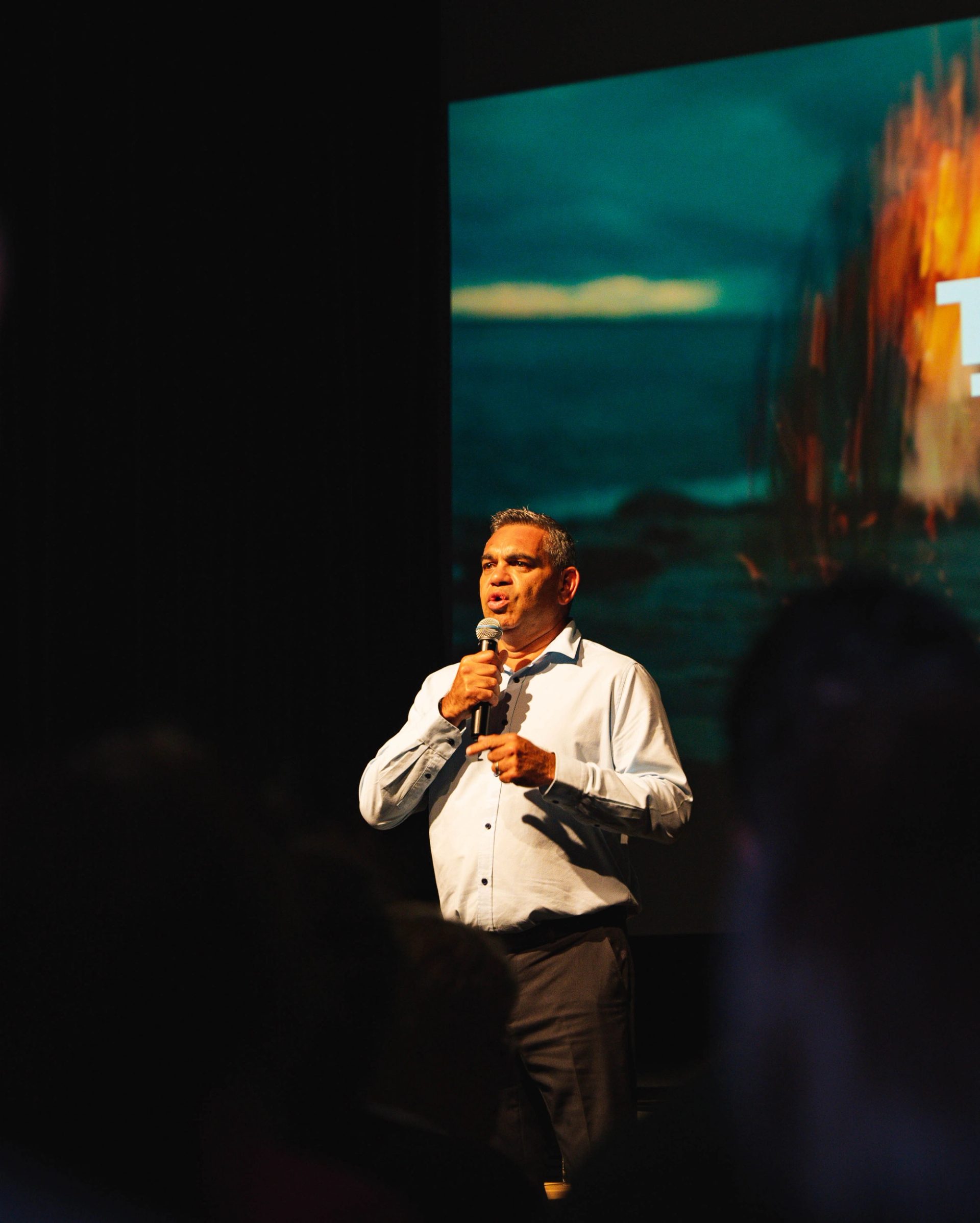 A man is standing on a stage and holding a microphone.
