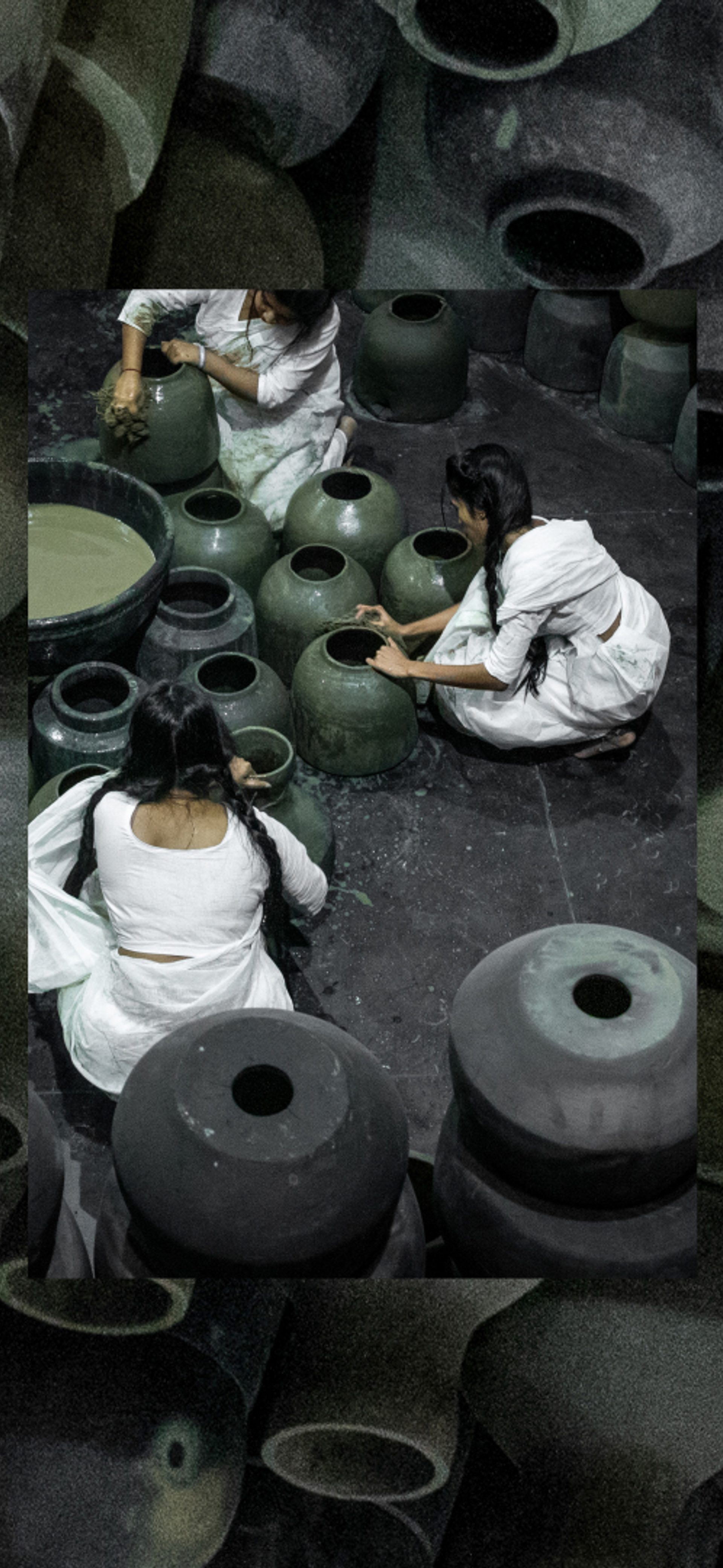 Five people dressed in white sit on the floor around black pots and surrounded by black pots.
