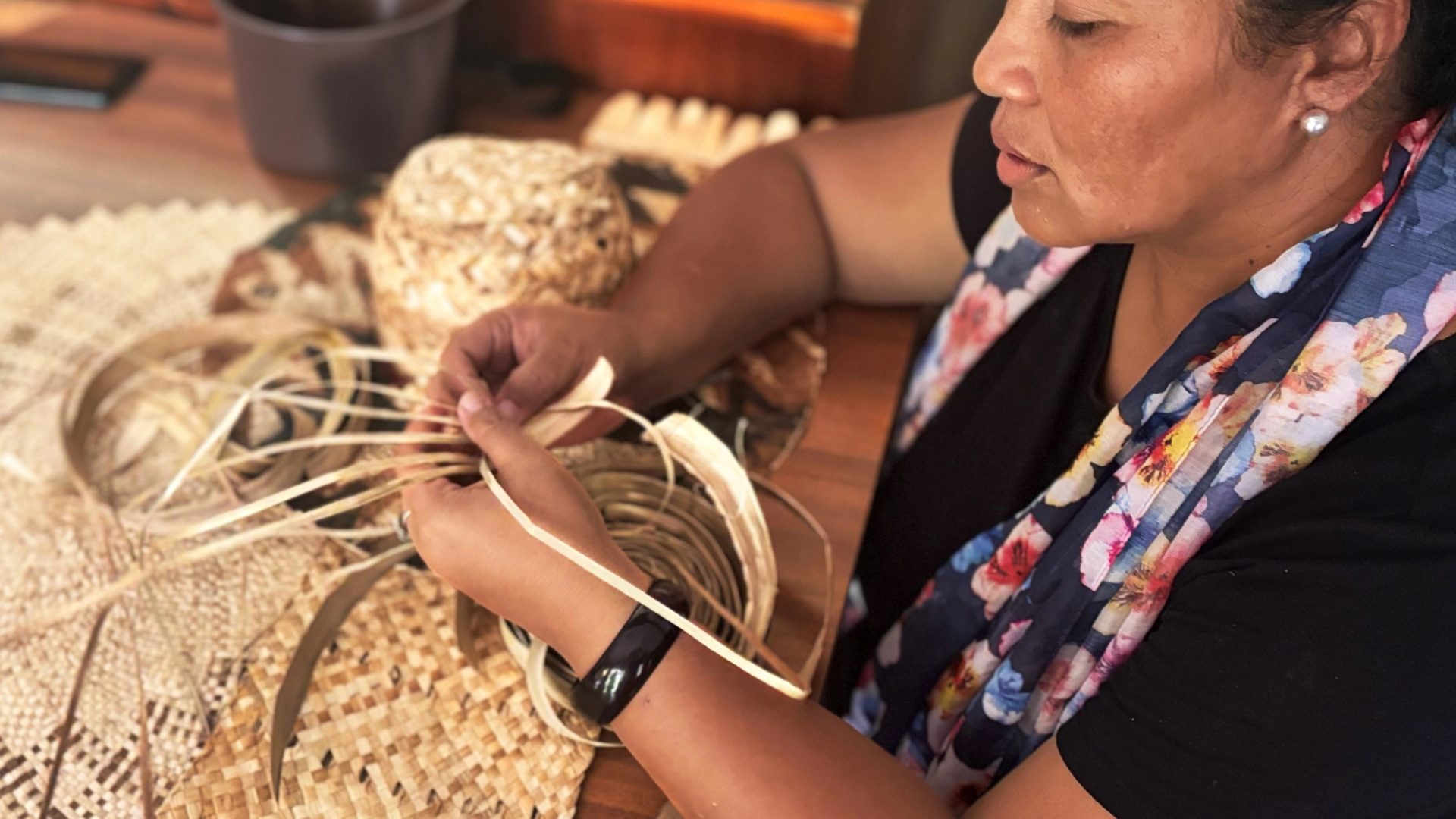 Woman weaving while sitting down at a table.
