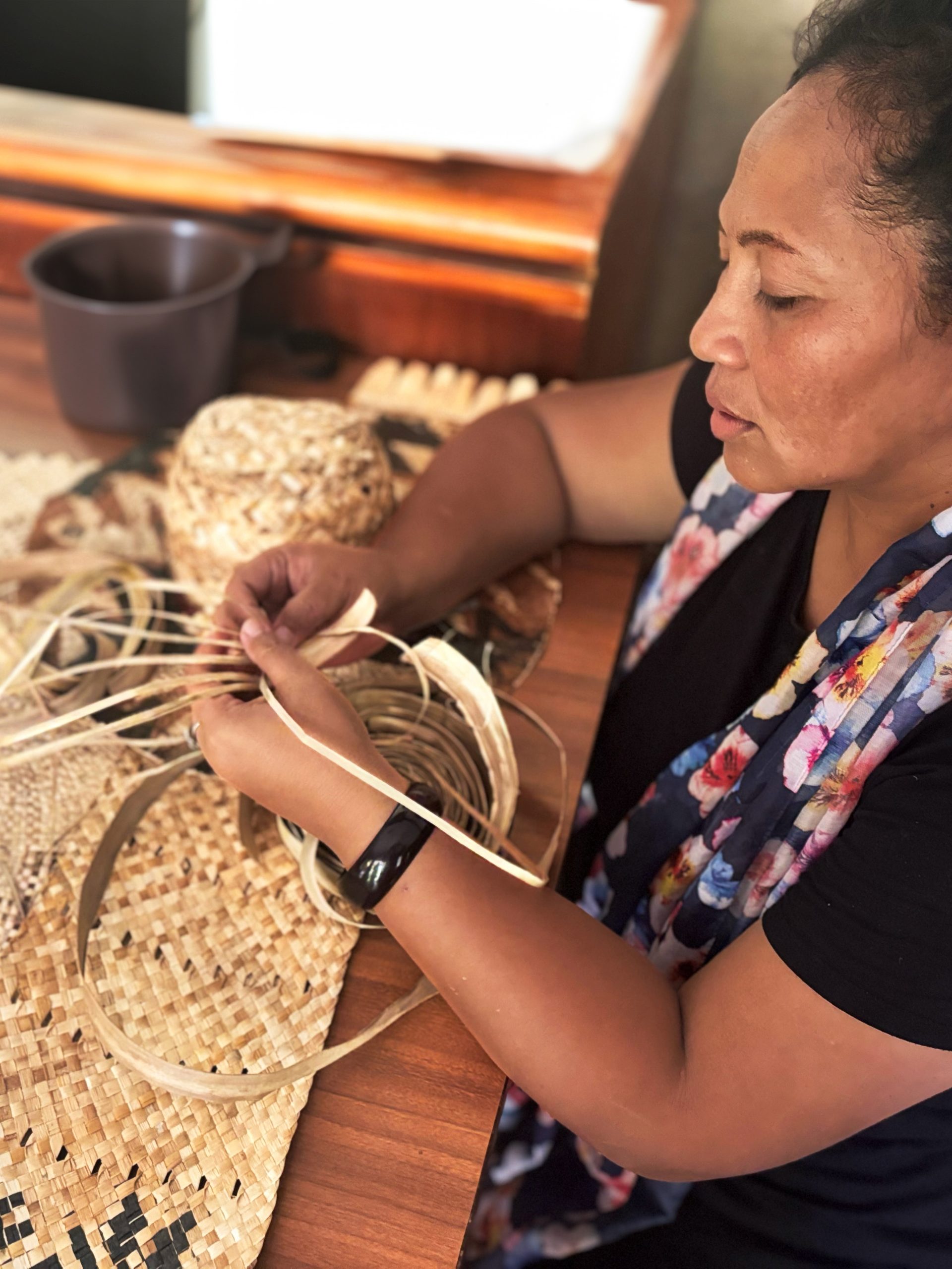 Woman weaving while sitting down at a table.