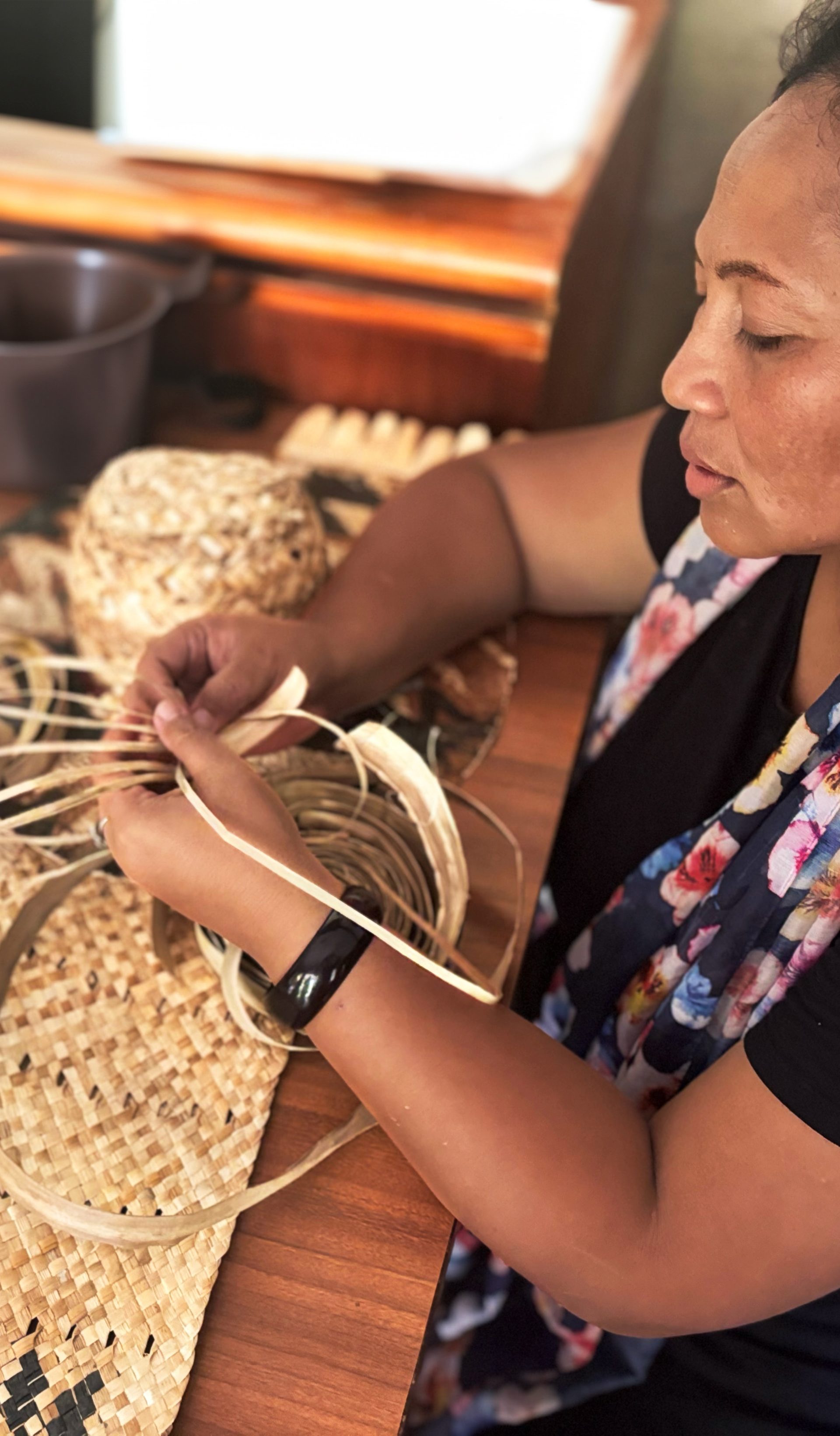 Woman weaving while sitting down at a table.