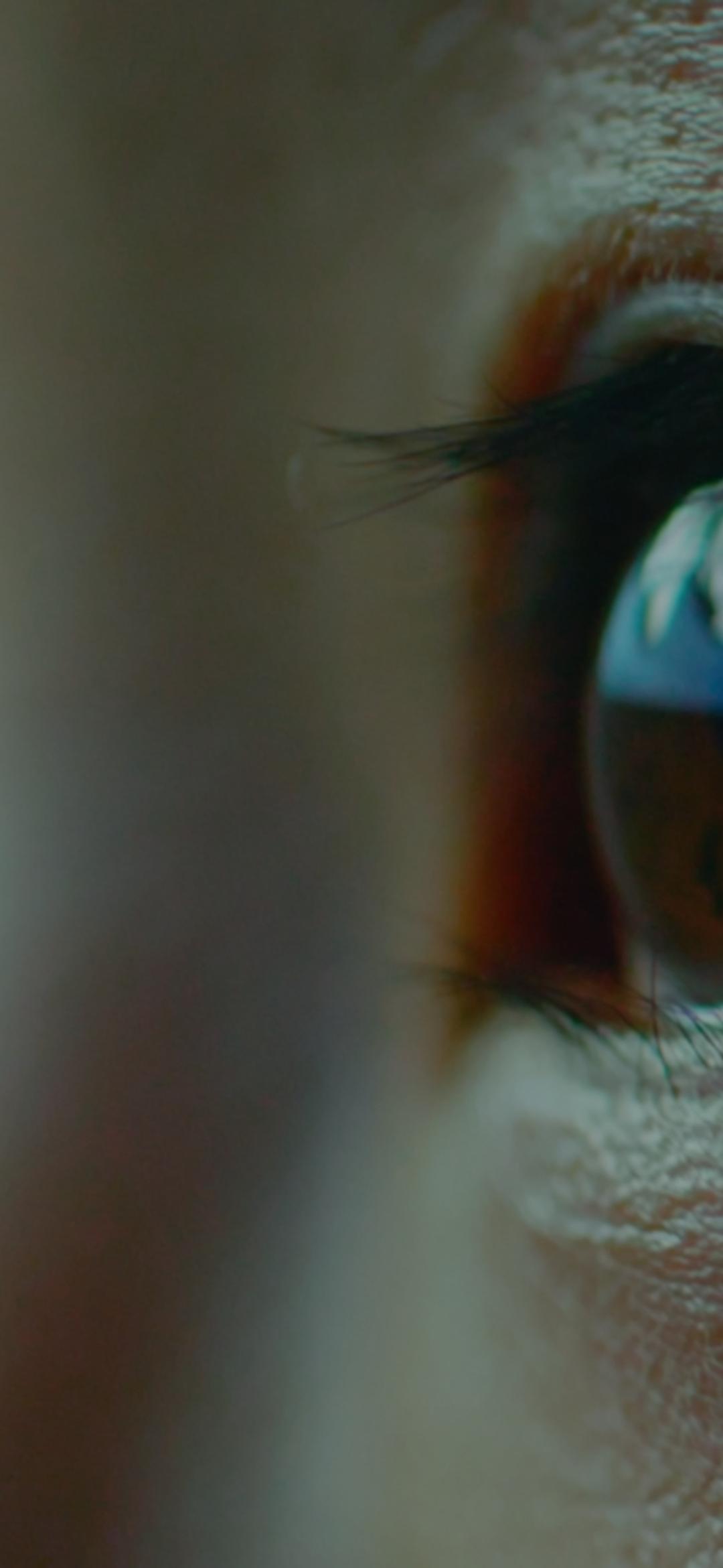 Close up of eyes looking upwards with the corner of a screen reflected in the eye