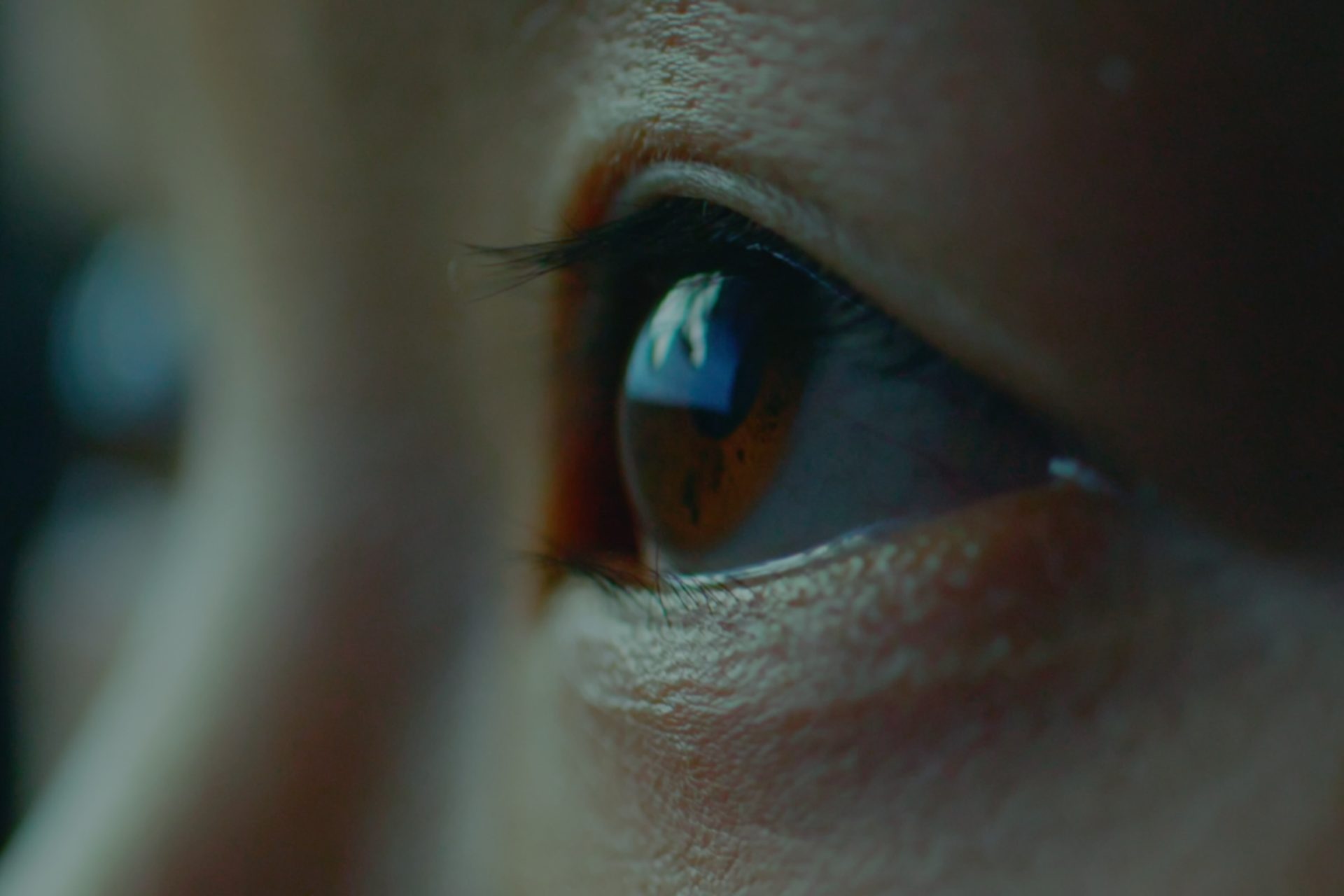 Close up of eyes looking upwards with the corner of a screen reflected in the eye