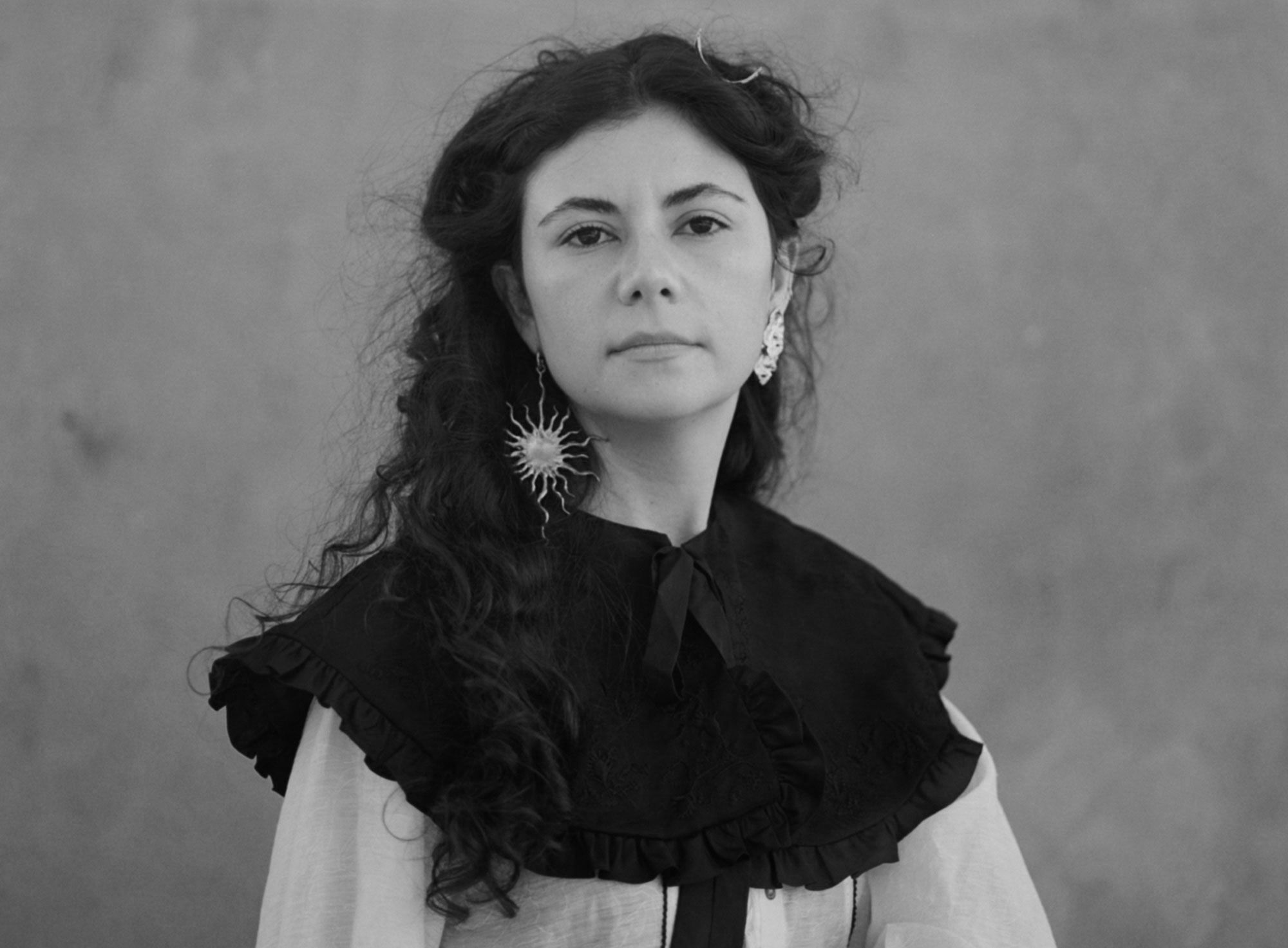 Indira Elias looking at the camera, wearing a Sun-like earring.